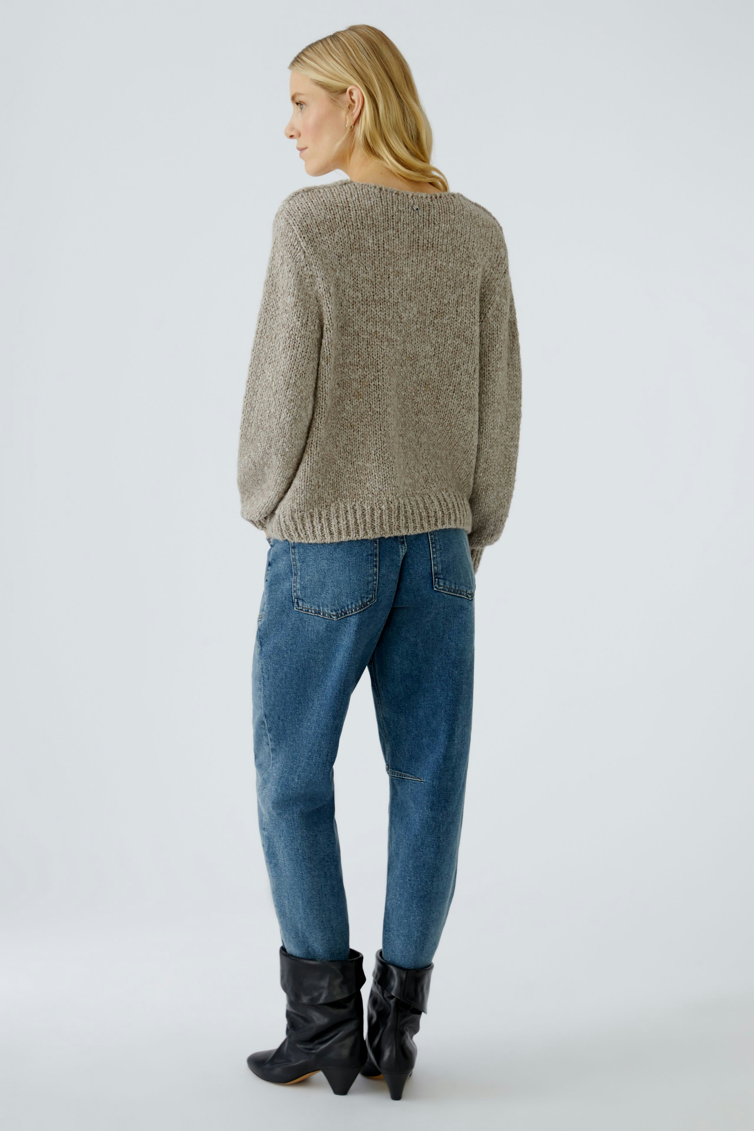 Casual women's pullover: A woman in a cozy beige pullover with relaxed fit and blue jeans.