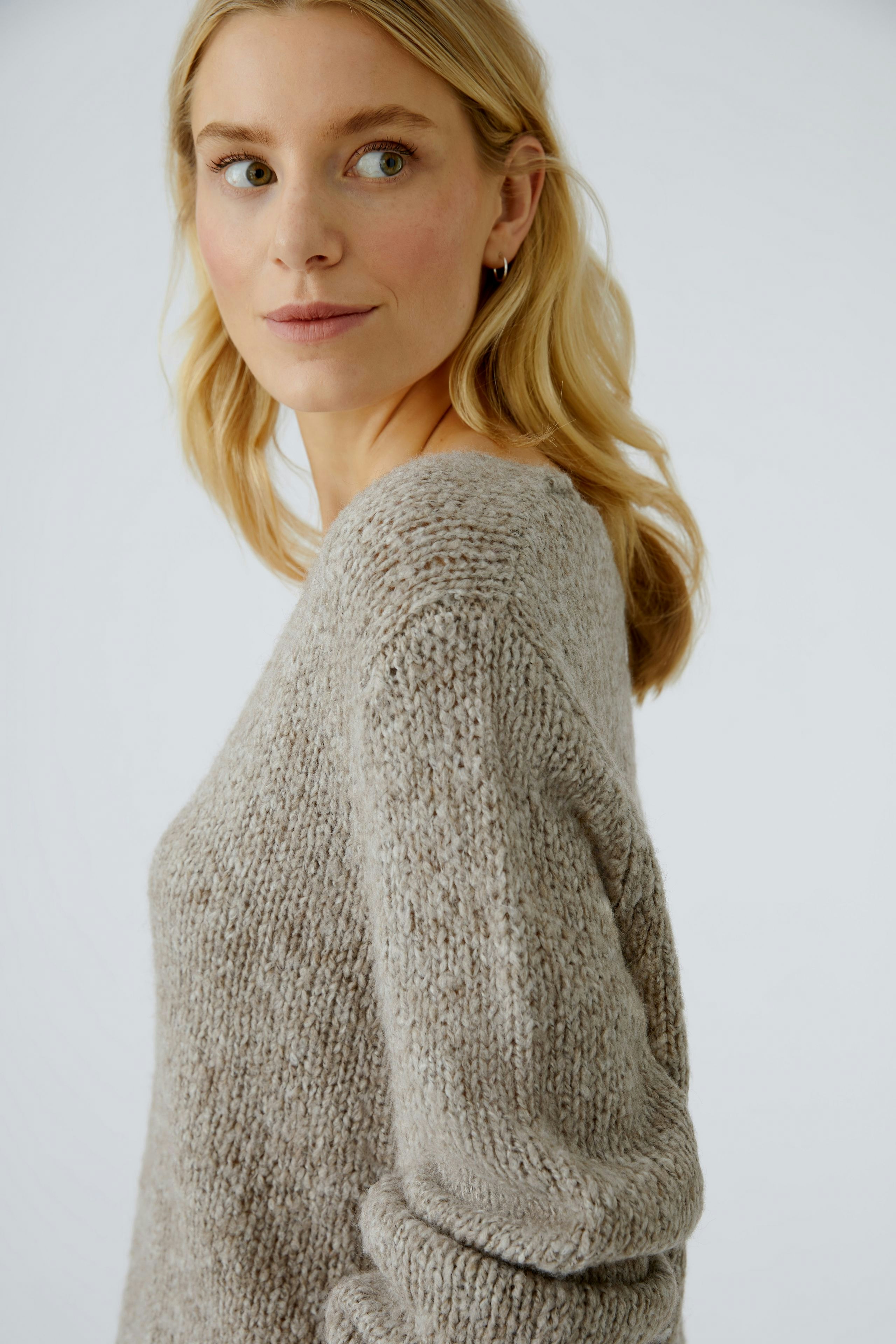 Casual women's pullover: A woman in a soft, light brown knit pullover with a relaxed fit.