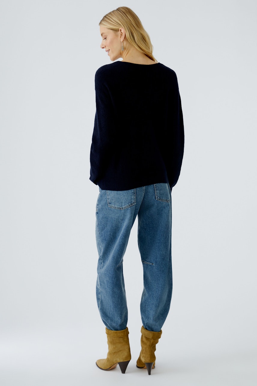 Casual women's pullover: A woman in a navy pullover and relaxed jeans, showcasing a laid-back style.
