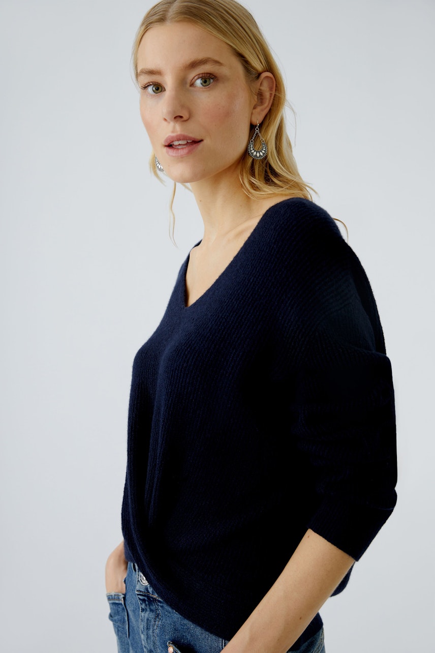 Casual women's pullover: Young woman in a navy V-neck pullover with relaxed fit and rolled sleeves.