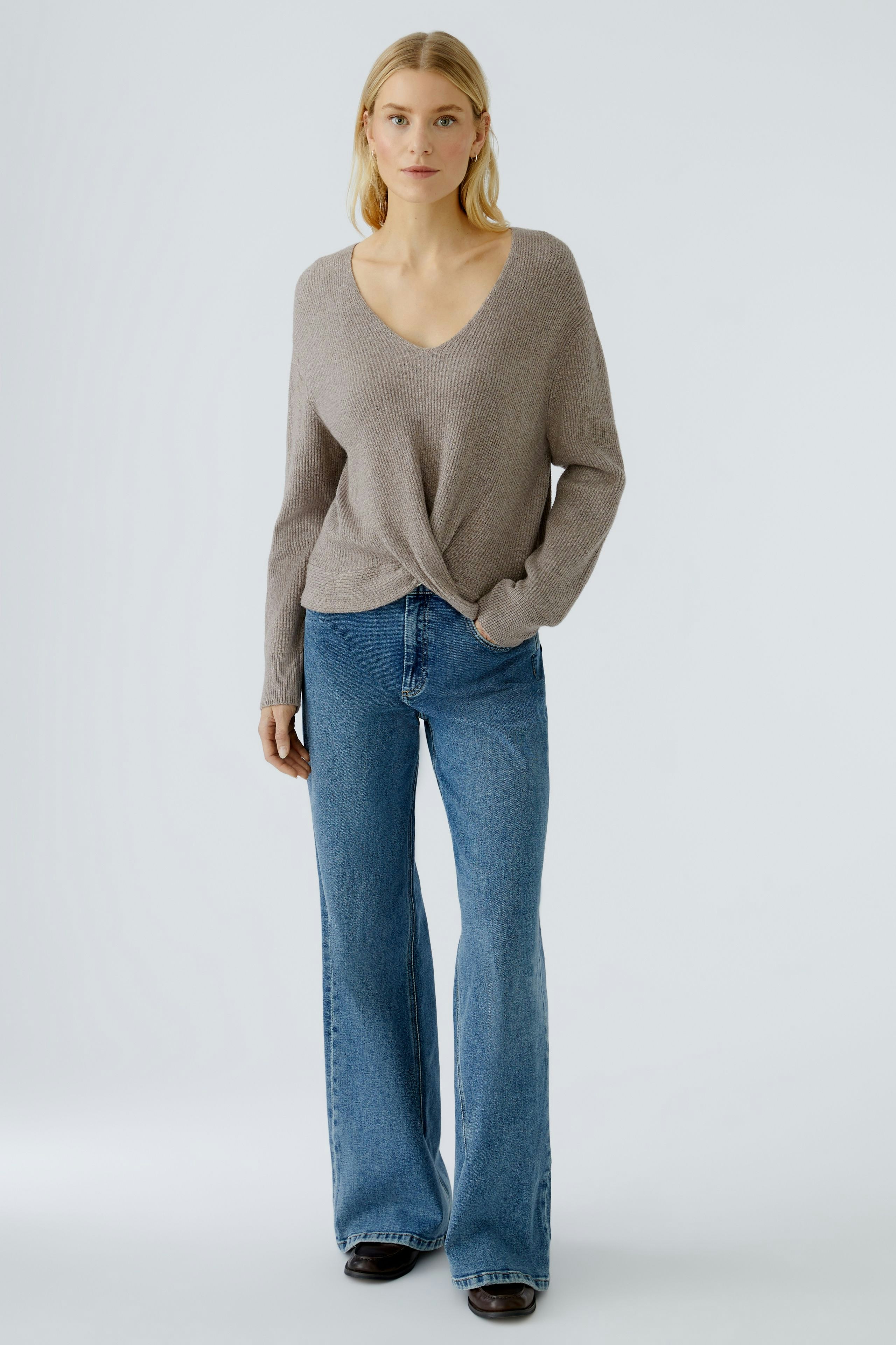 Casual women's pullover: A woman in a light brown pullover with a V-neck and relaxed fit.