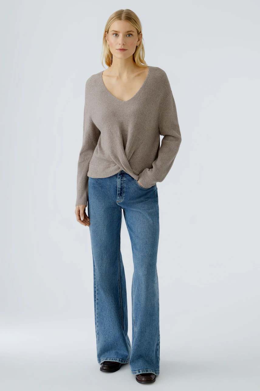 Casual women's pullover: A woman in a light brown pullover with a V-neck and relaxed fit.