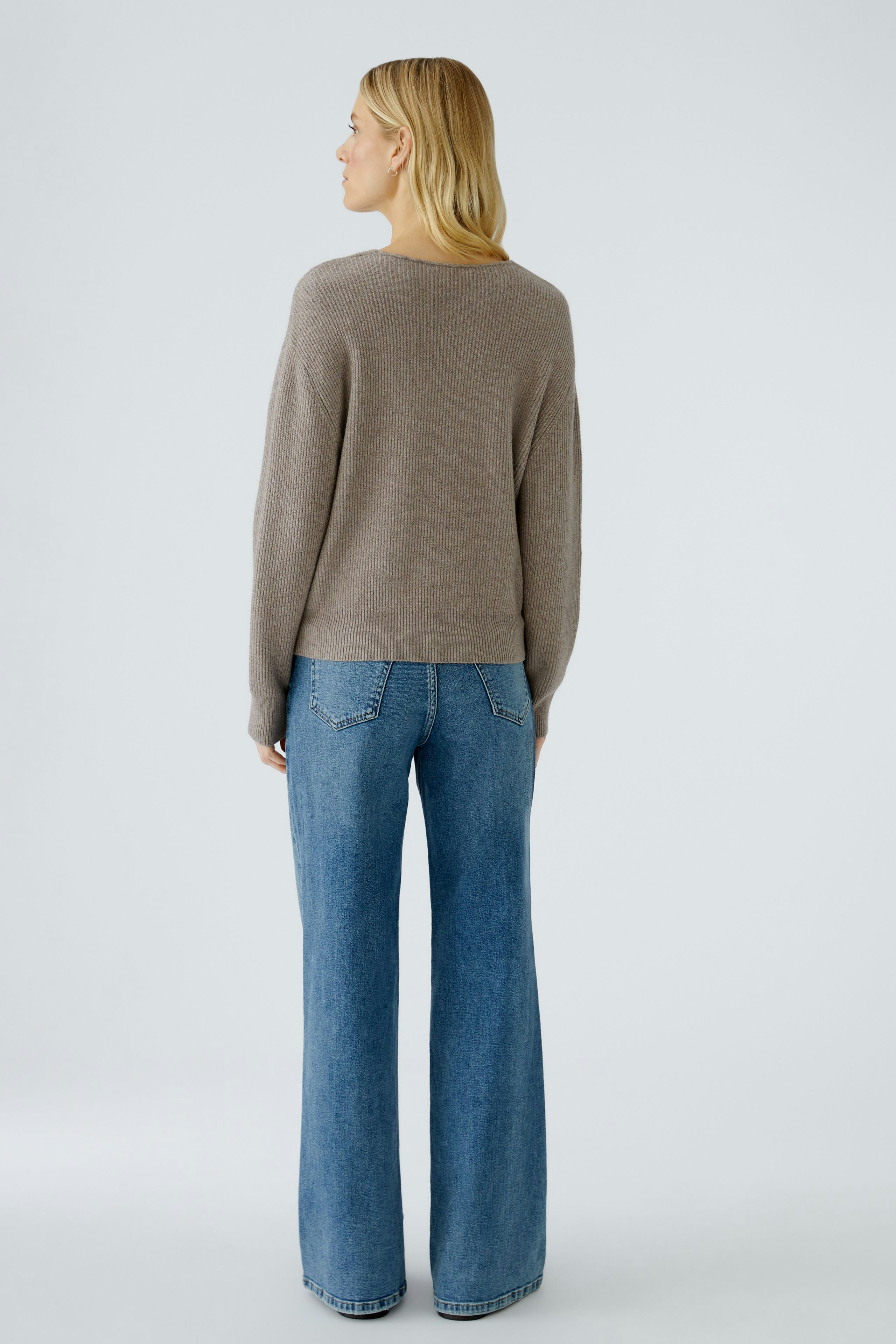 Casual women's pullover: A woman in a soft brown pullover paired with flared jeans, showcasing a relaxed style.