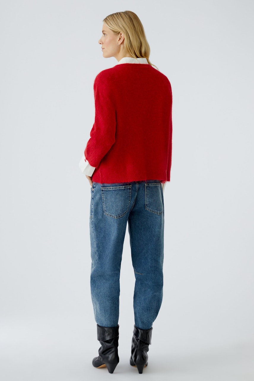 Damen-Pullover: Frau in rotem, lässigem Strickpullover mit weißen Details und Jeans.