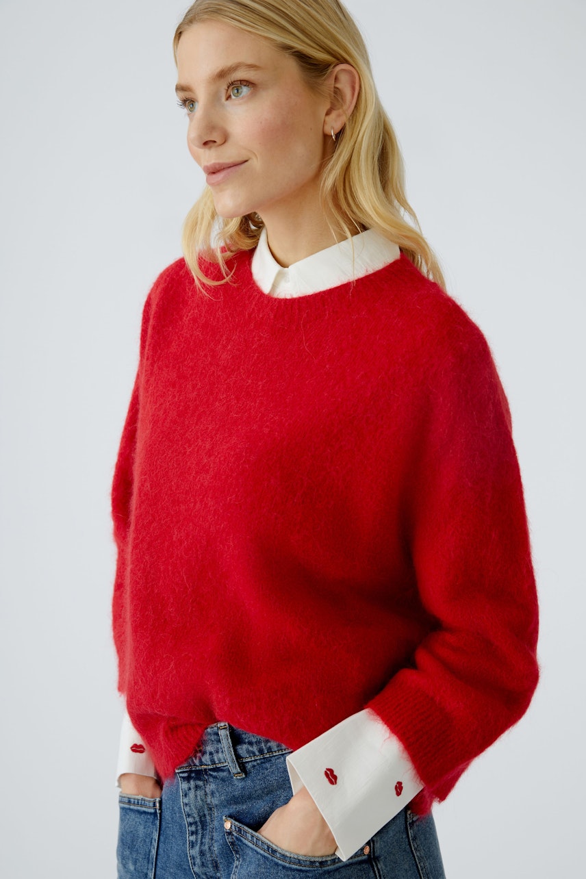 Damen-Pullover: Frau in rotem, weichem Strickpullover mit weißen Details und lässiger Jeans.