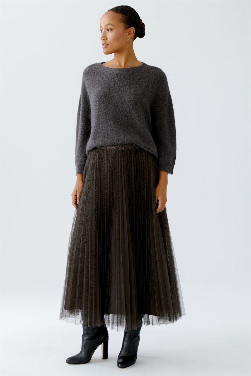 Damen-Pullover: Frau in grauem, weichem Strickpullover mit lässigem Schnitt und weitem Saum.