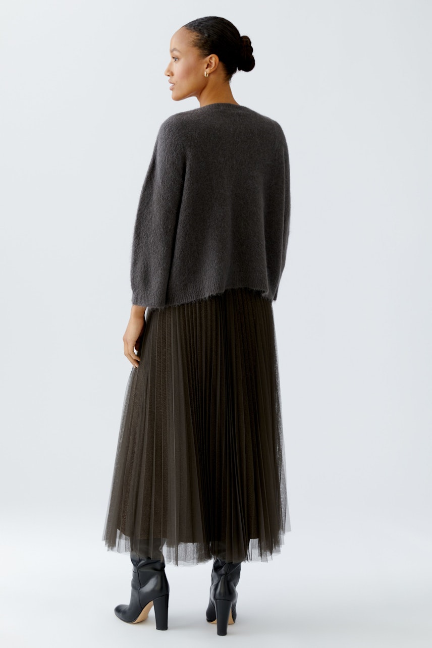 Damen-Pullover: Frau in grauem, lässigem Strickpullover mit weitem Schnitt und plissiertem Rock.