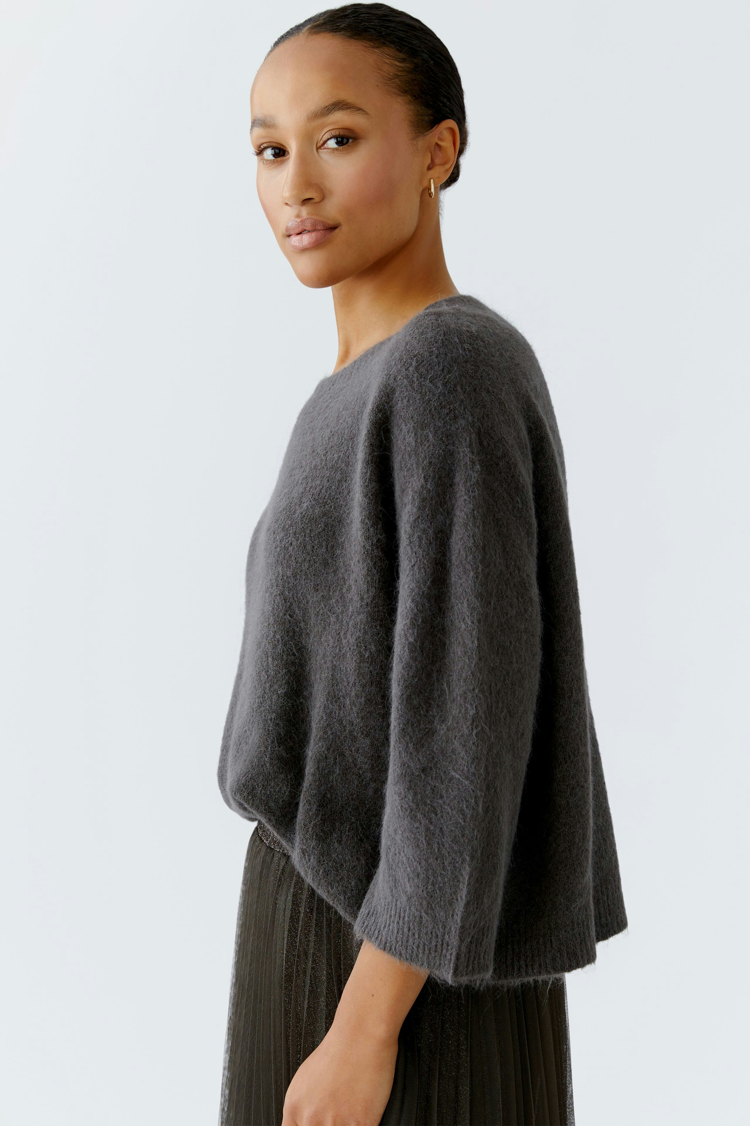 Casual women's pullover: Young woman in a cozy gray pullover with a relaxed fit.