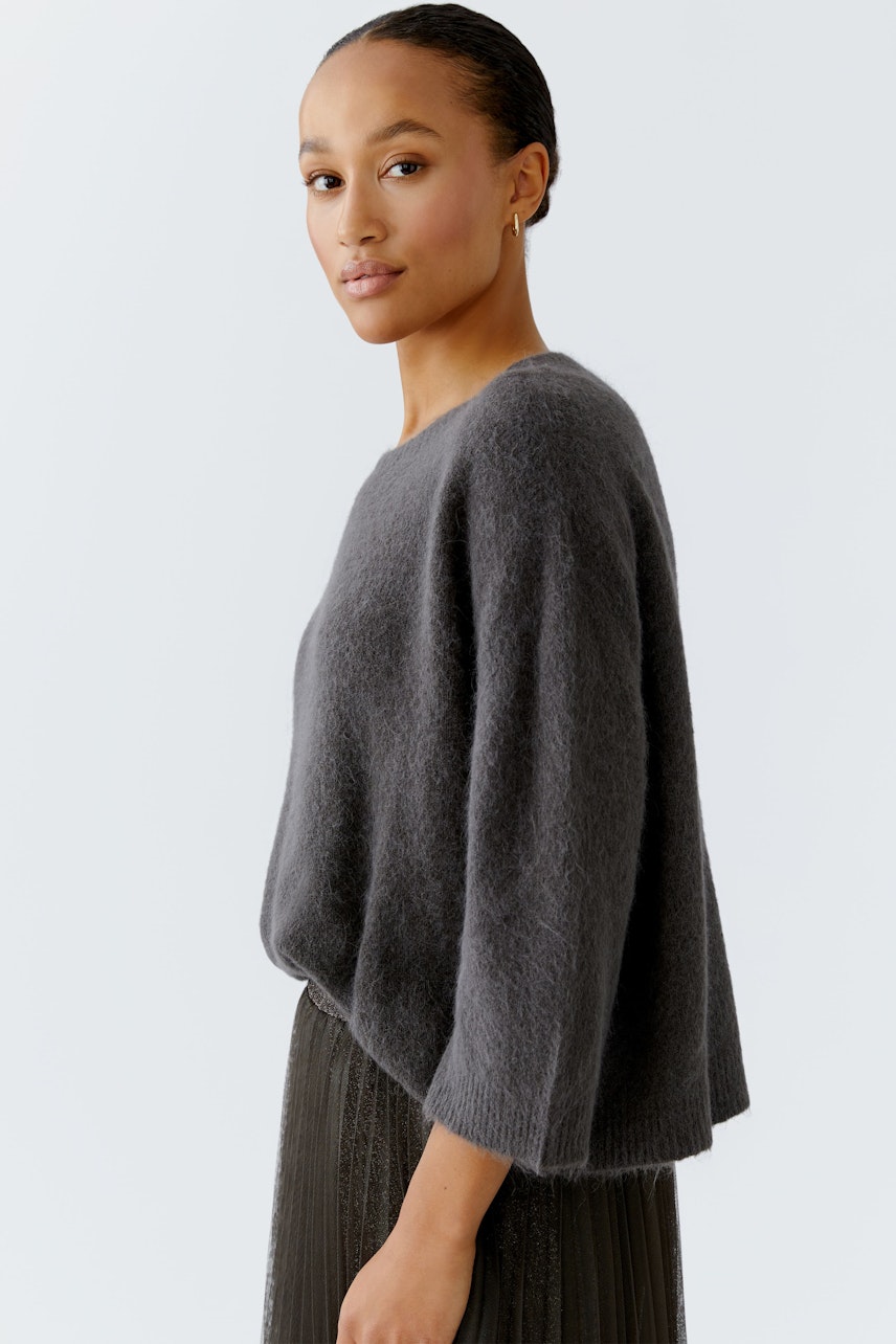 Damen-Pullover: Frau in grauem, lässigem Strickpullover mit weitem Schnitt und 3/4-Ärmeln.