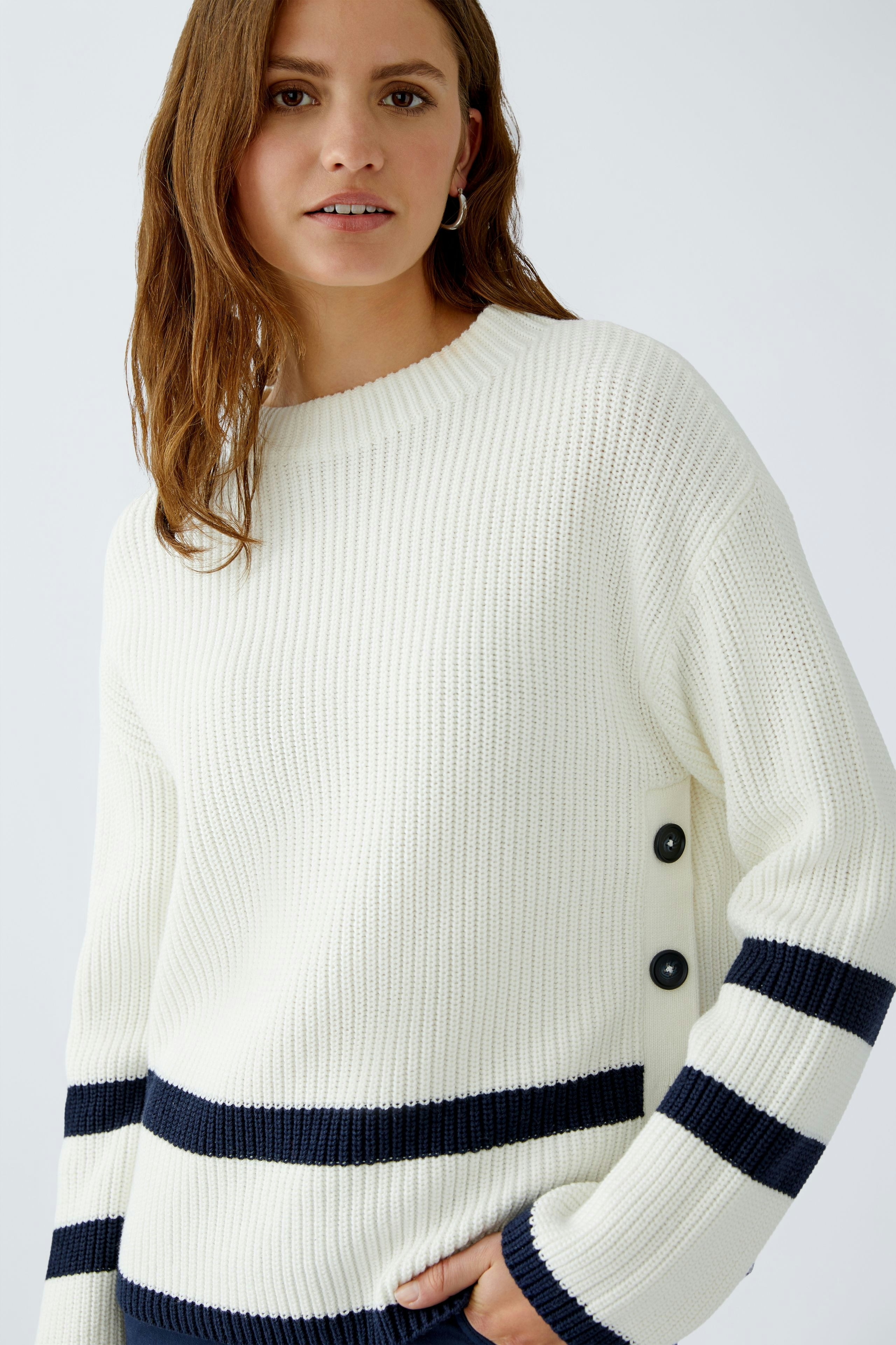 Casual women's pullover: A woman in a white ribbed pullover with navy stripes and button details.