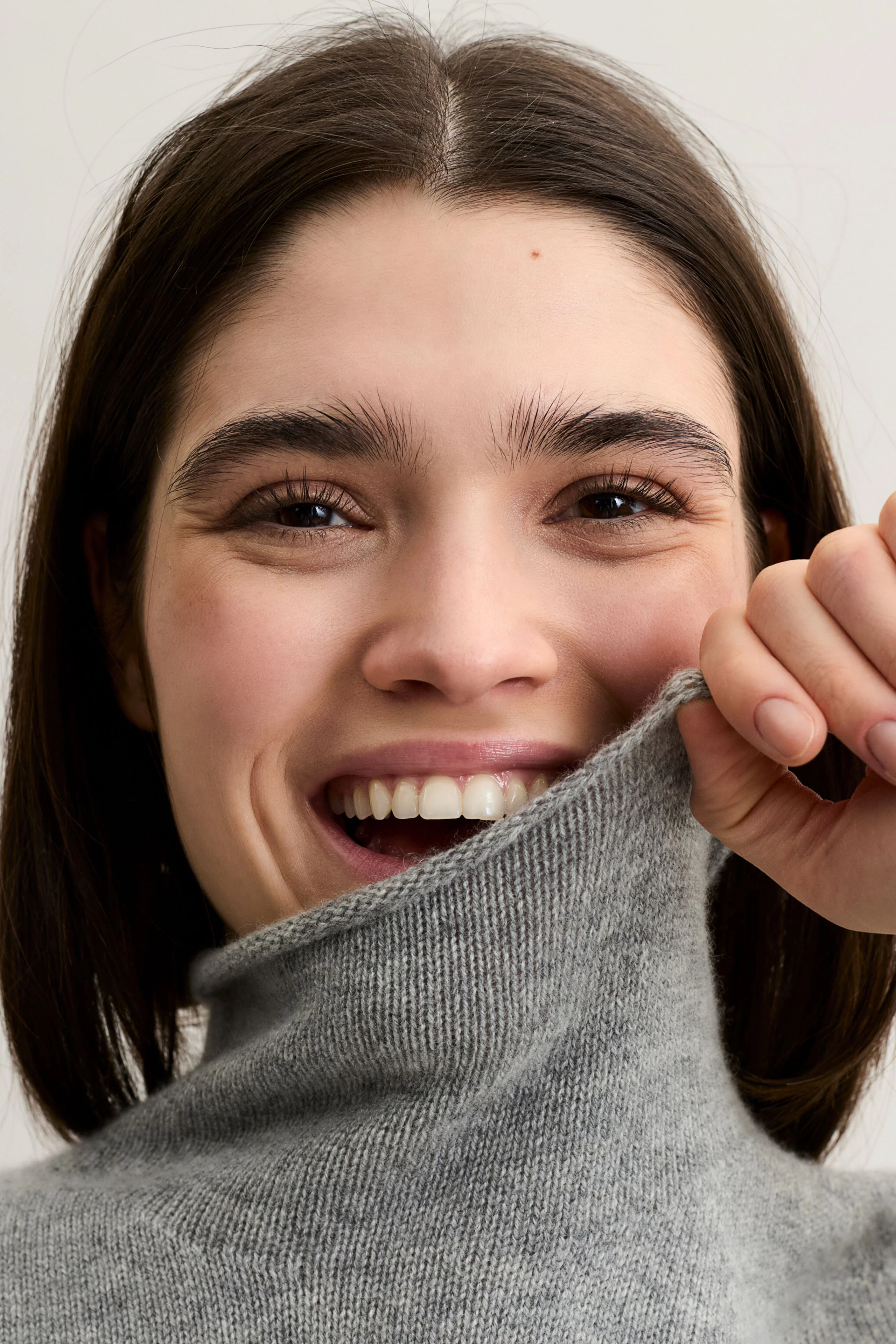 Bequemer Damen-Top: Junge Frau in grauem V-Ausschnitt-Top mit Spitzenunterkante und lässigen Jeans.