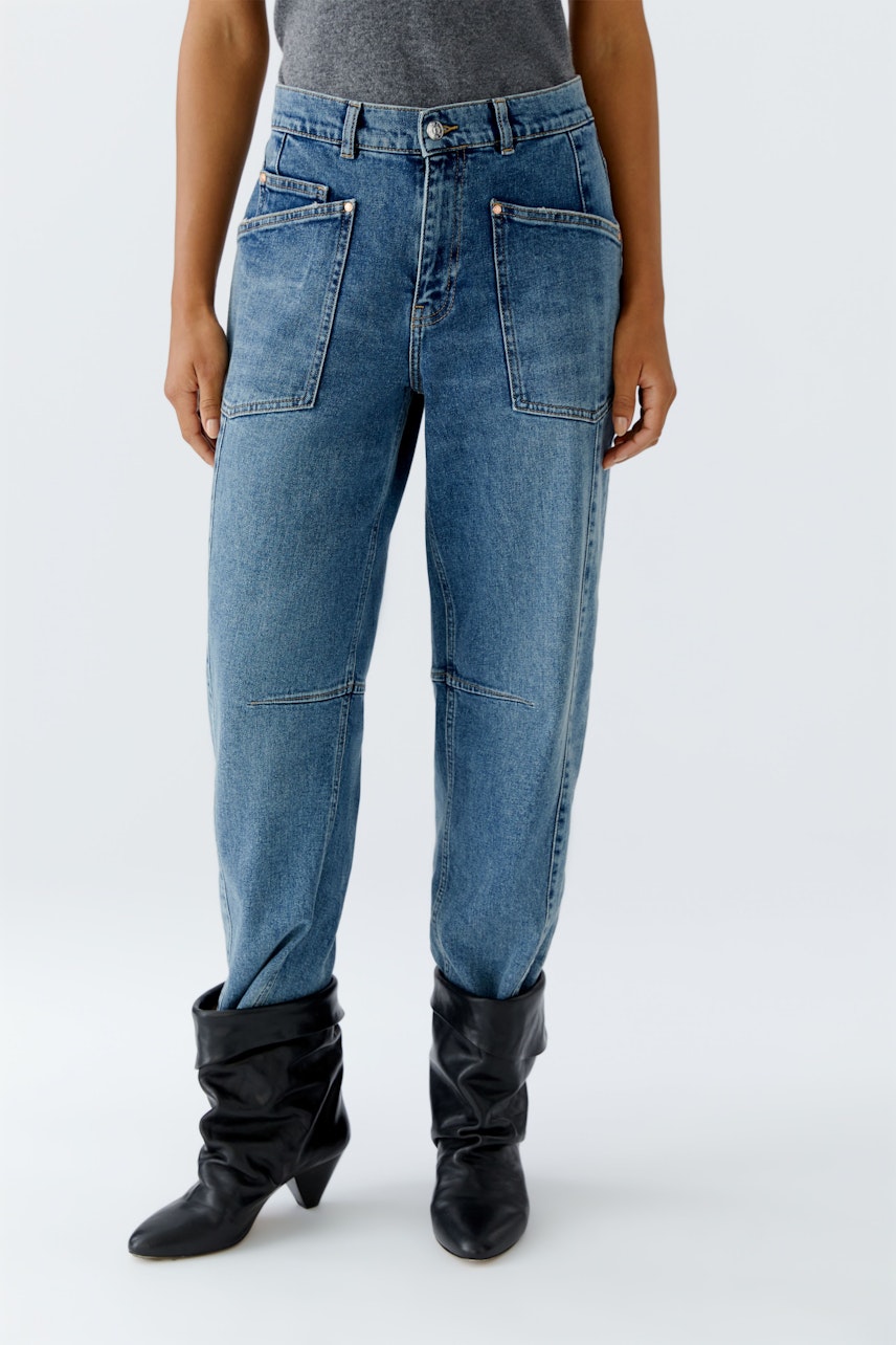 Casual women's jeans: A woman in blue barrel jeans with front pockets stands confidently.