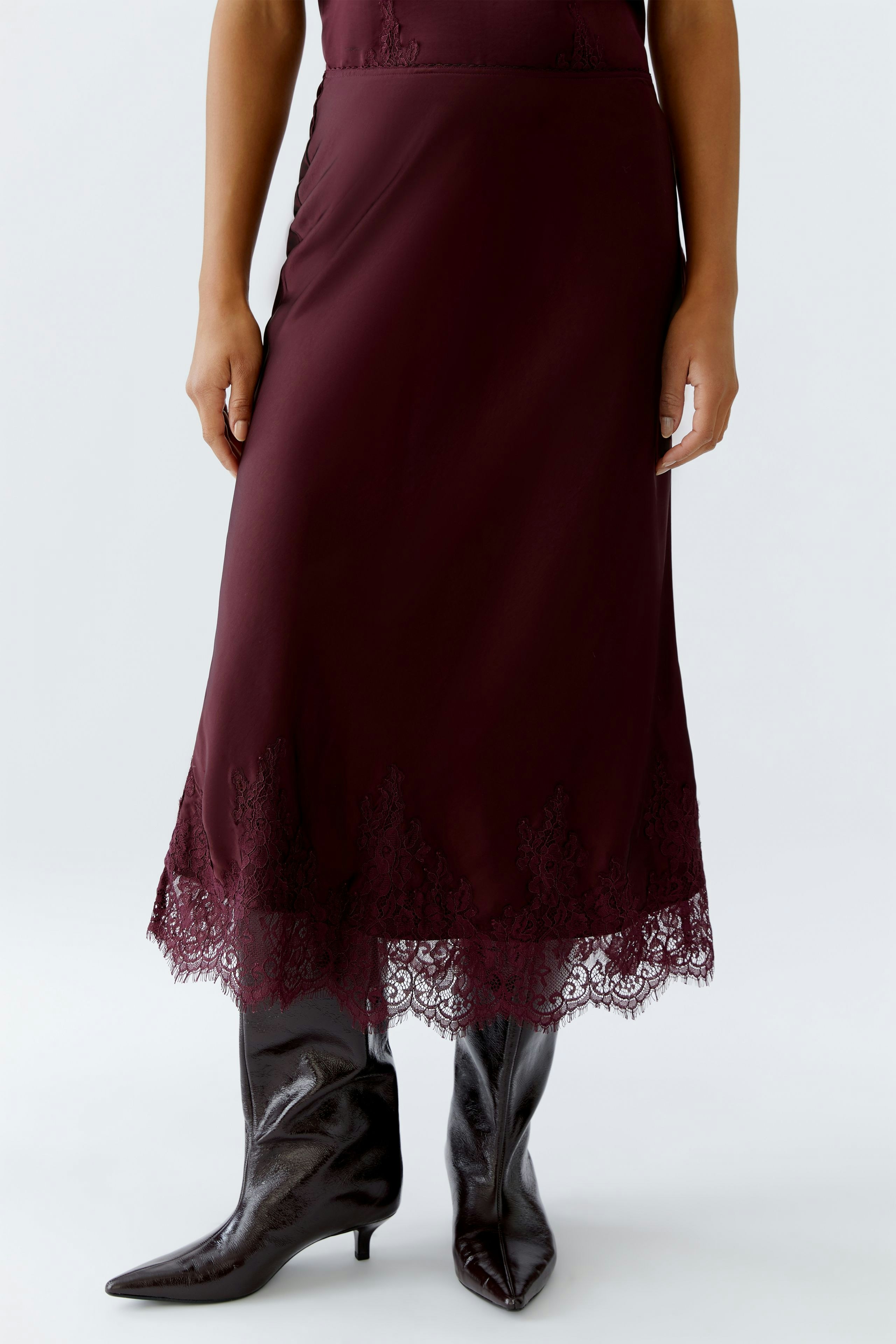 A-line skirt: Woman in a burgundy skirt with lace trim, paired with stylish knee-high boots.