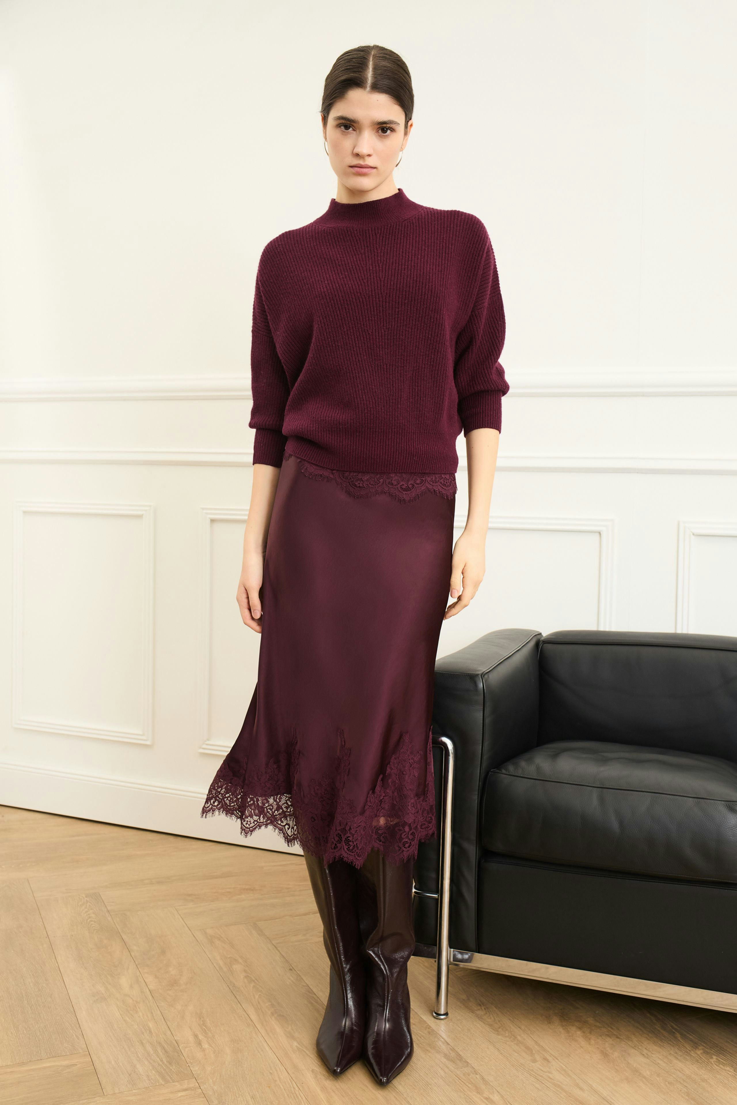 A-line skirt: Woman wearing a burgundy top and a grey wrap around her waist, showcasing a casual style.