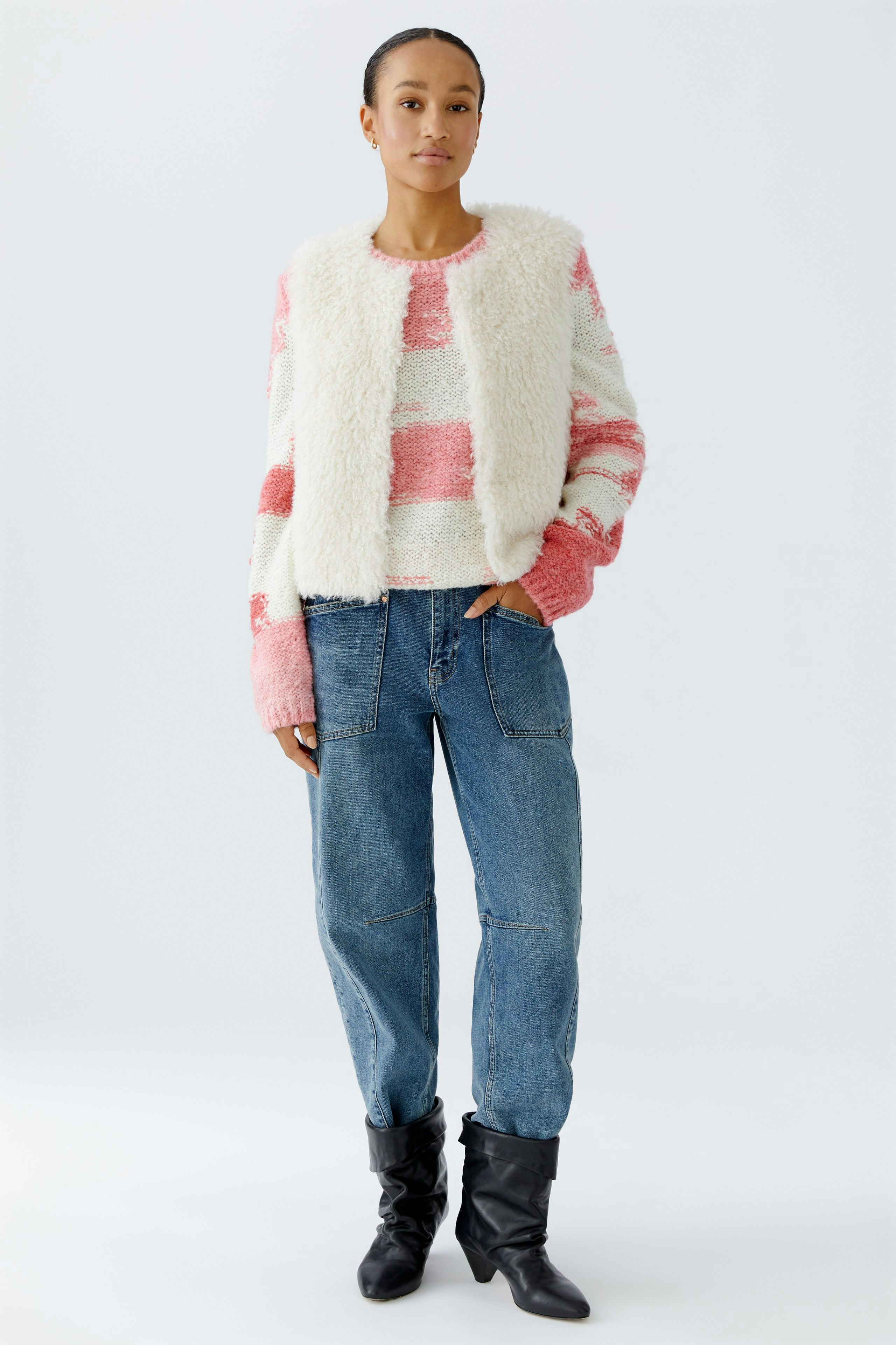 Cozy women's vest: A woman in a fluffy vest over a striped pullover, paired with relaxed jeans.