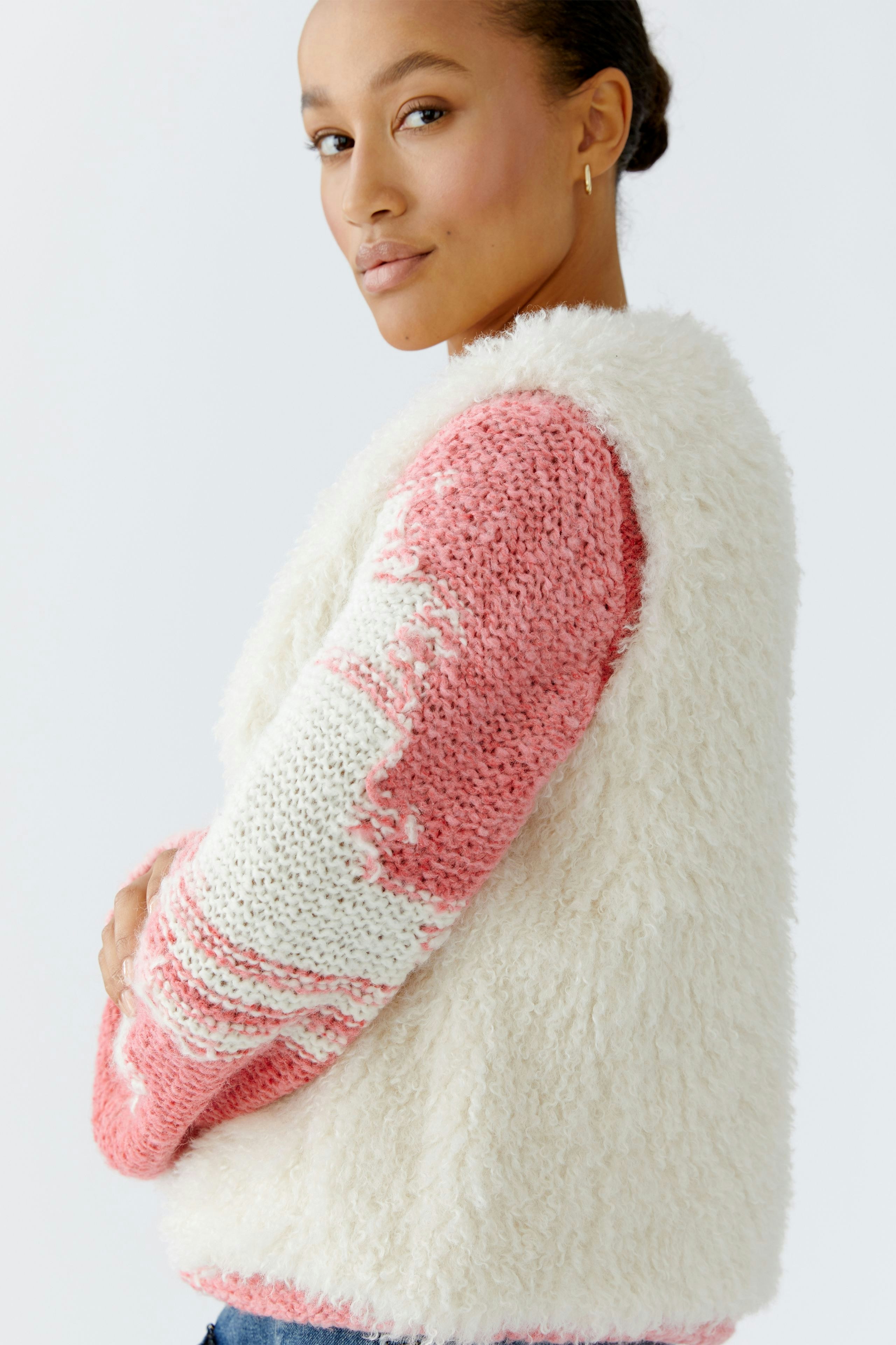 Cozy women's vest: A woman in a fluffy, pink and white knitted vest, showcasing a relaxed style.