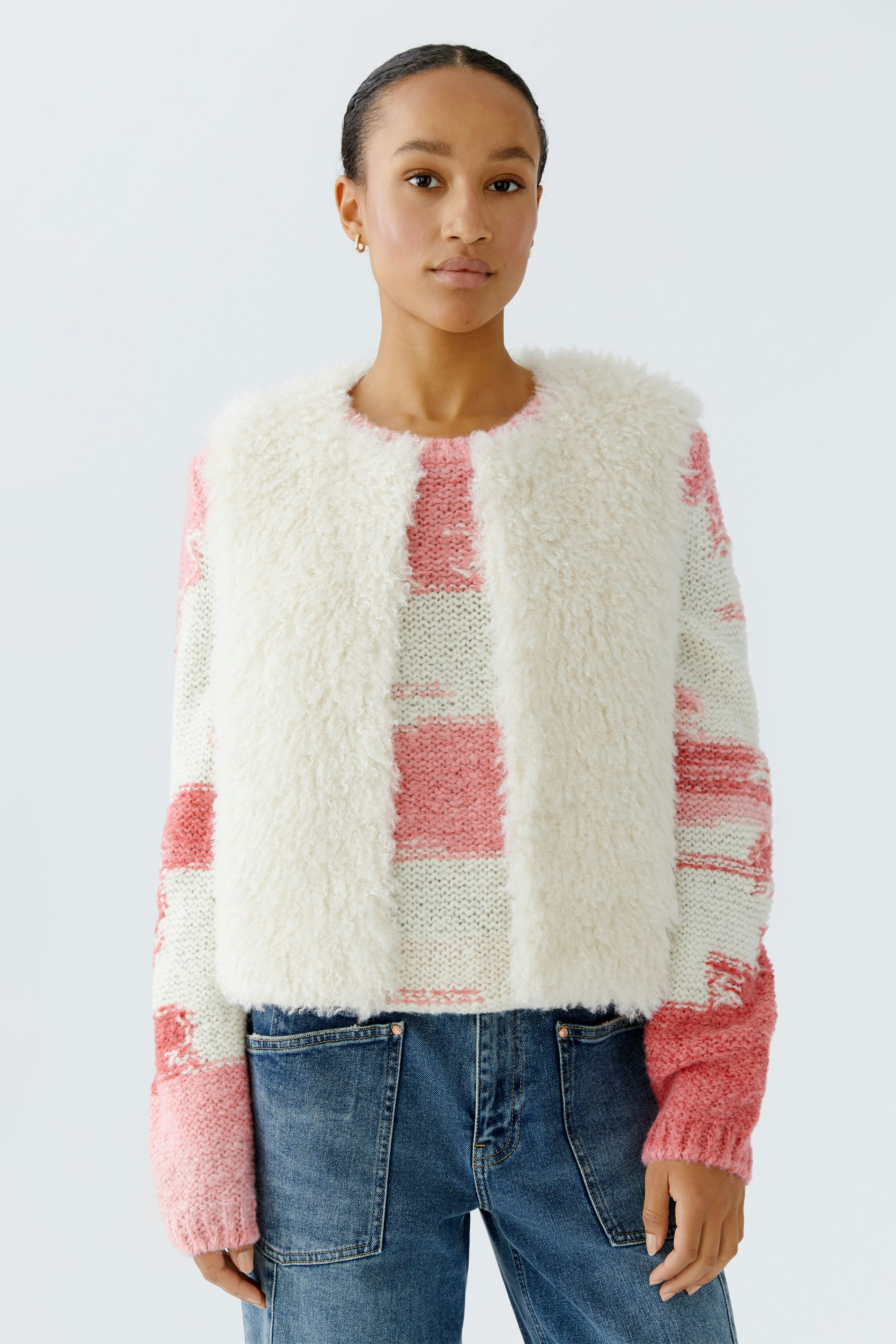 Casual women's vest: A woman in a fluffy, color-blocked vest over a knitted pullover and jeans.
