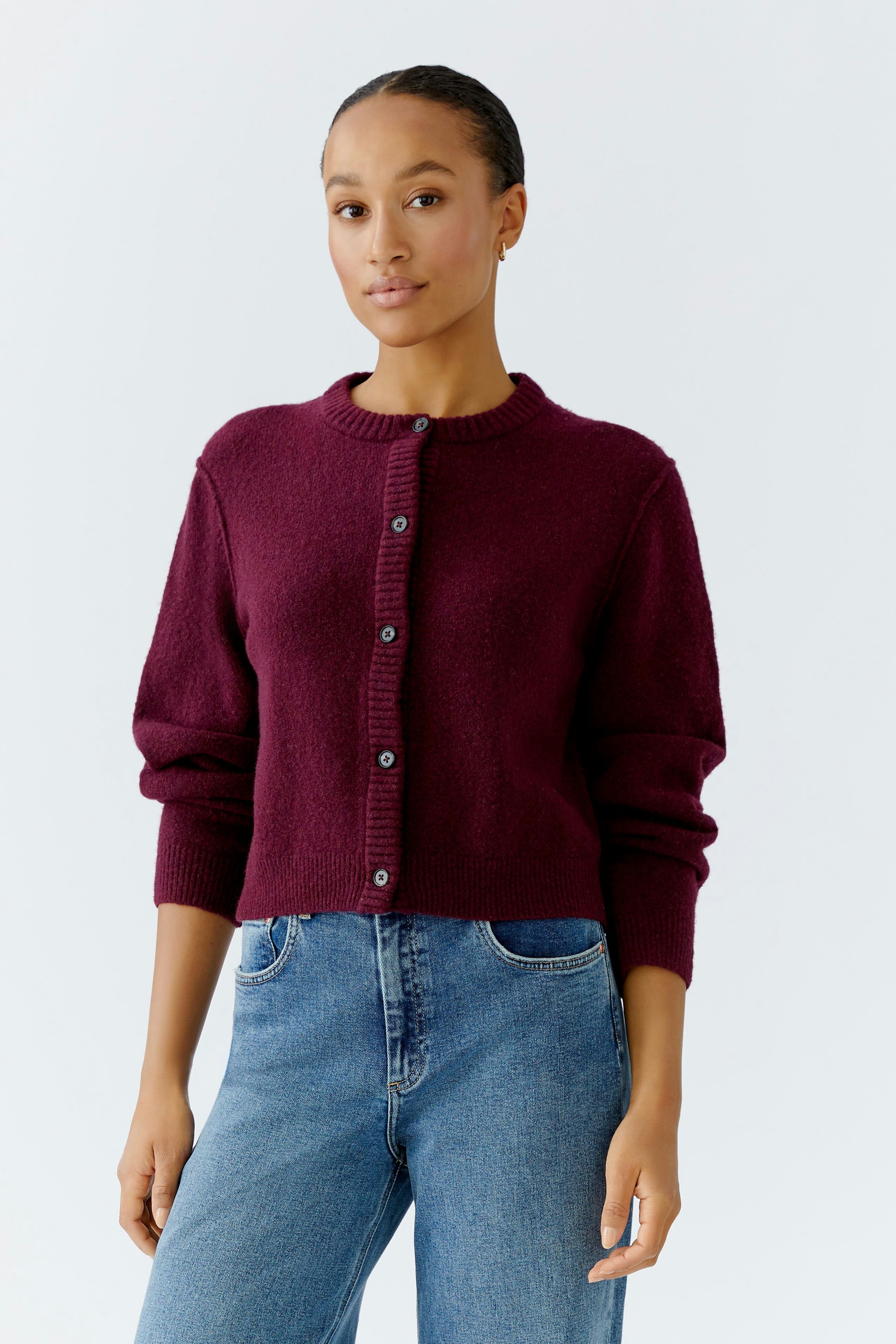 Casual women's cardigan: Young woman in a burgundy cardigan with buttons, paired with blue jeans.