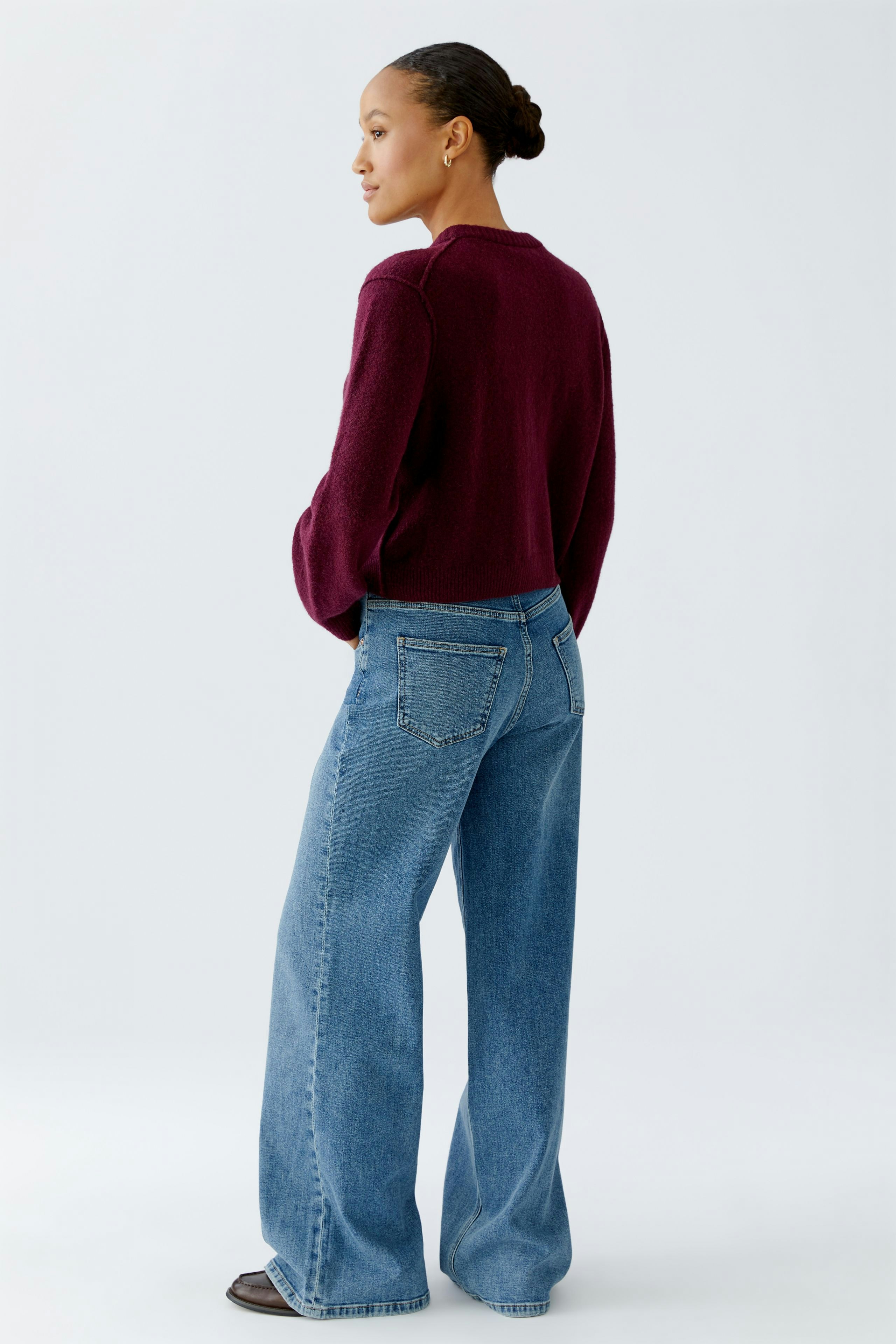 Casual women's cardigan: A woman in a burgundy cardigan paired with wide-leg jeans, showcasing a relaxed style.