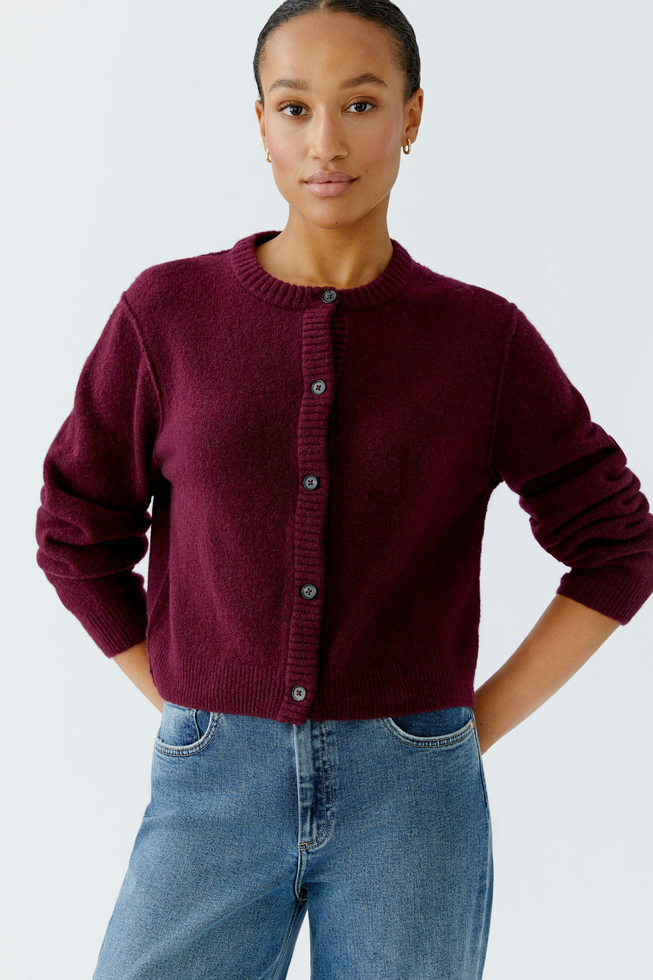 Casual women's cardigan: A woman in a burgundy cardigan with buttons, paired with blue jeans.