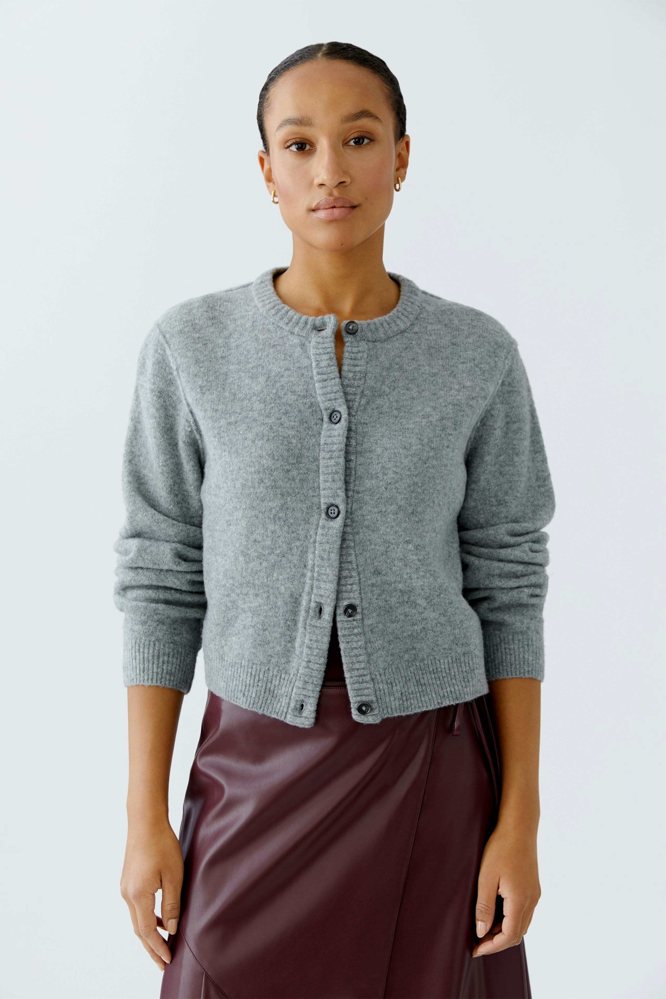 Casual women's cardigan: A woman in a gray cardigan with buttons, paired with a burgundy skirt.