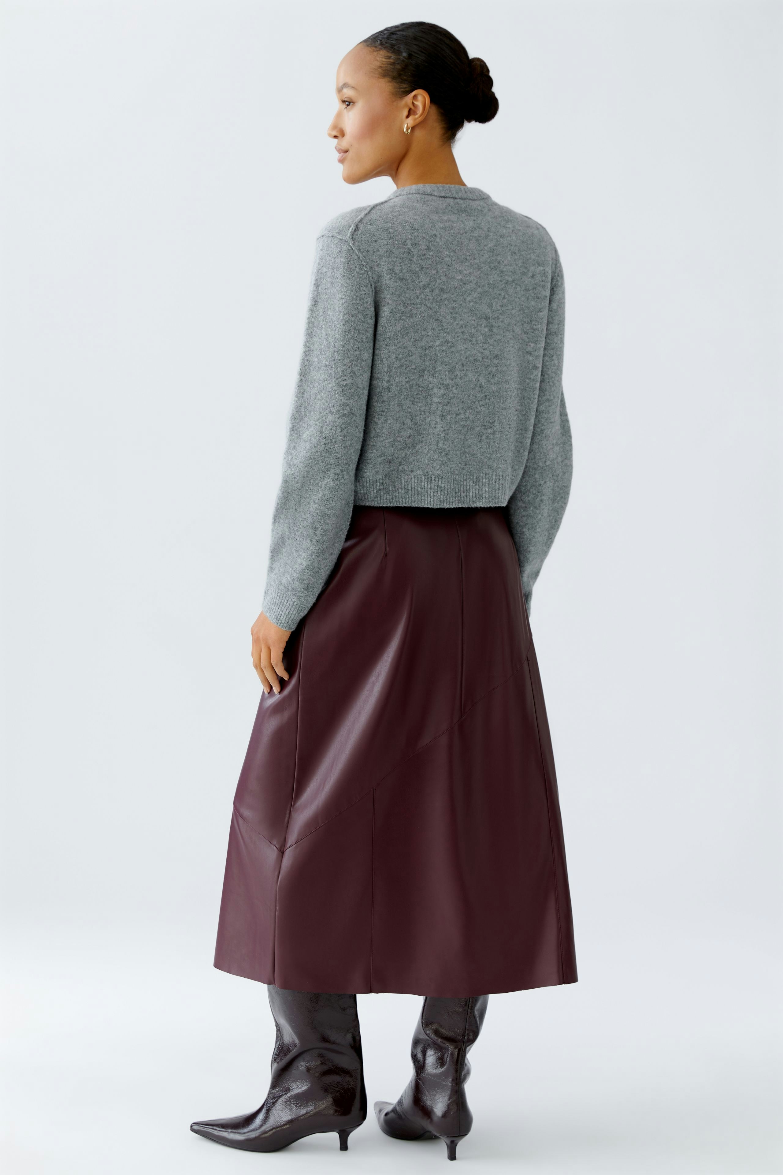 Casual women's cardigan: A woman in a gray knitted cardigan paired with a burgundy skirt.