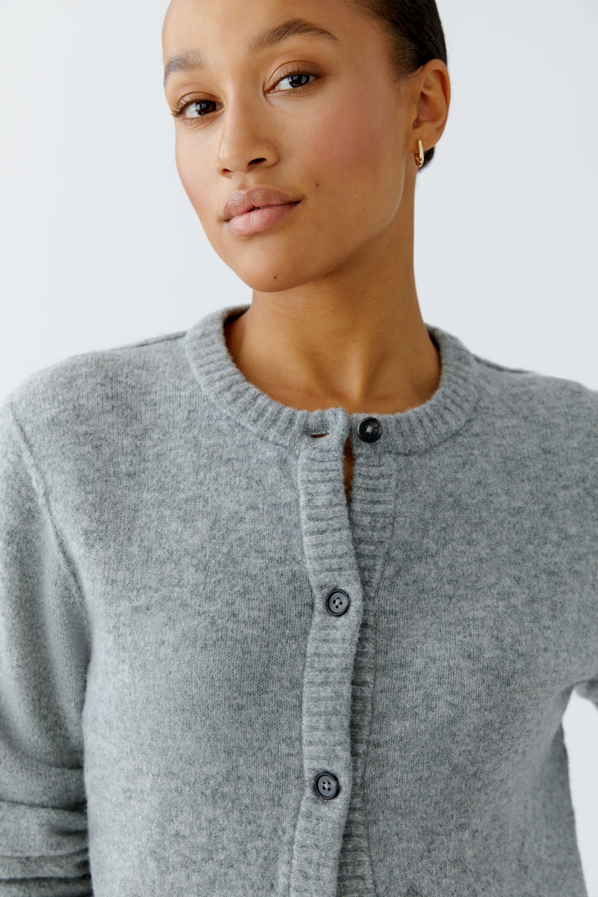 Gemütliche Damen-Strickjacke: Frau in grauer Strickjacke mit Knöpfen und Rundhalsausschnitt.