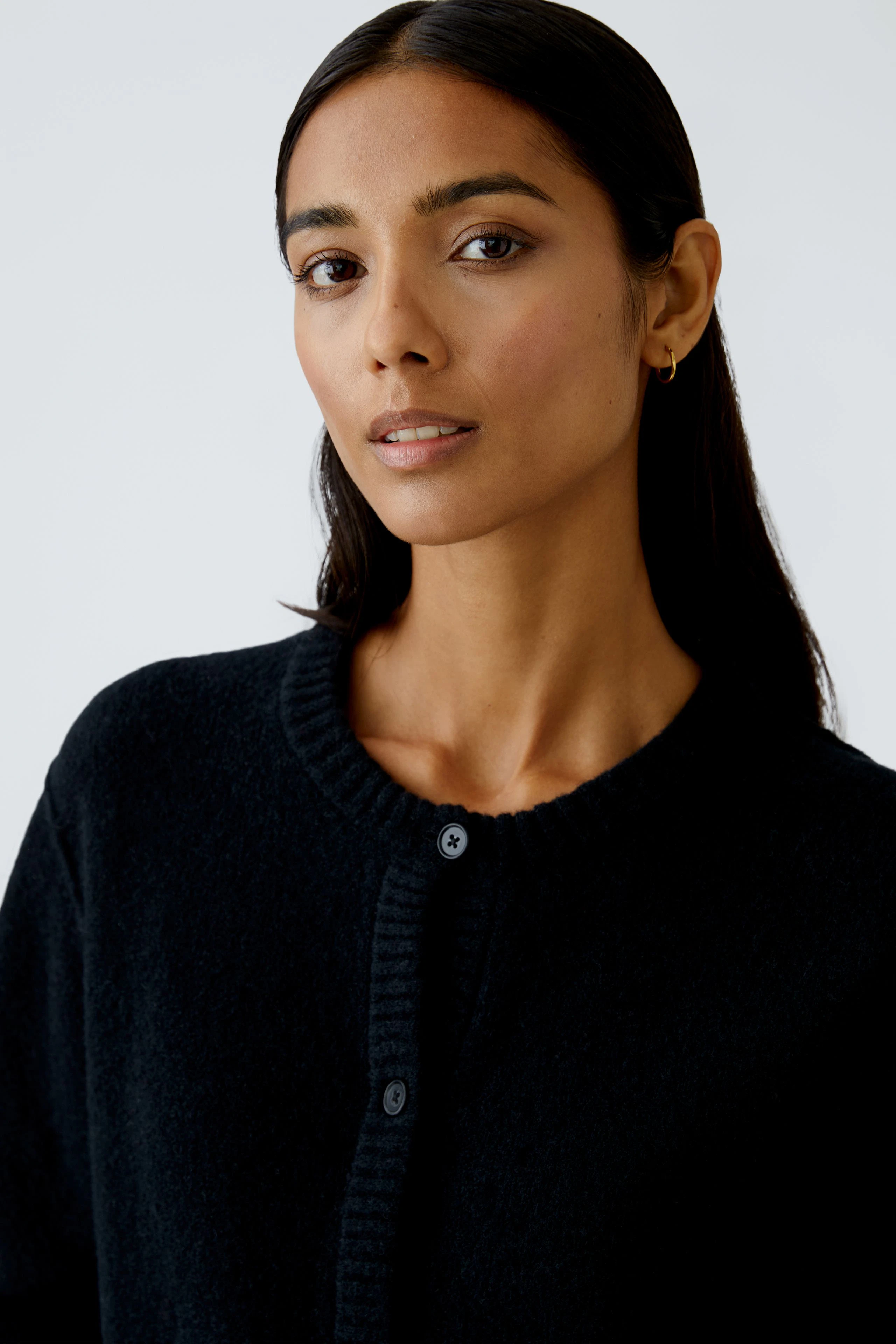 Damen-Strickjacke: Frau in schwarzer Strickjacke mit Knöpfen, lässiger Look.