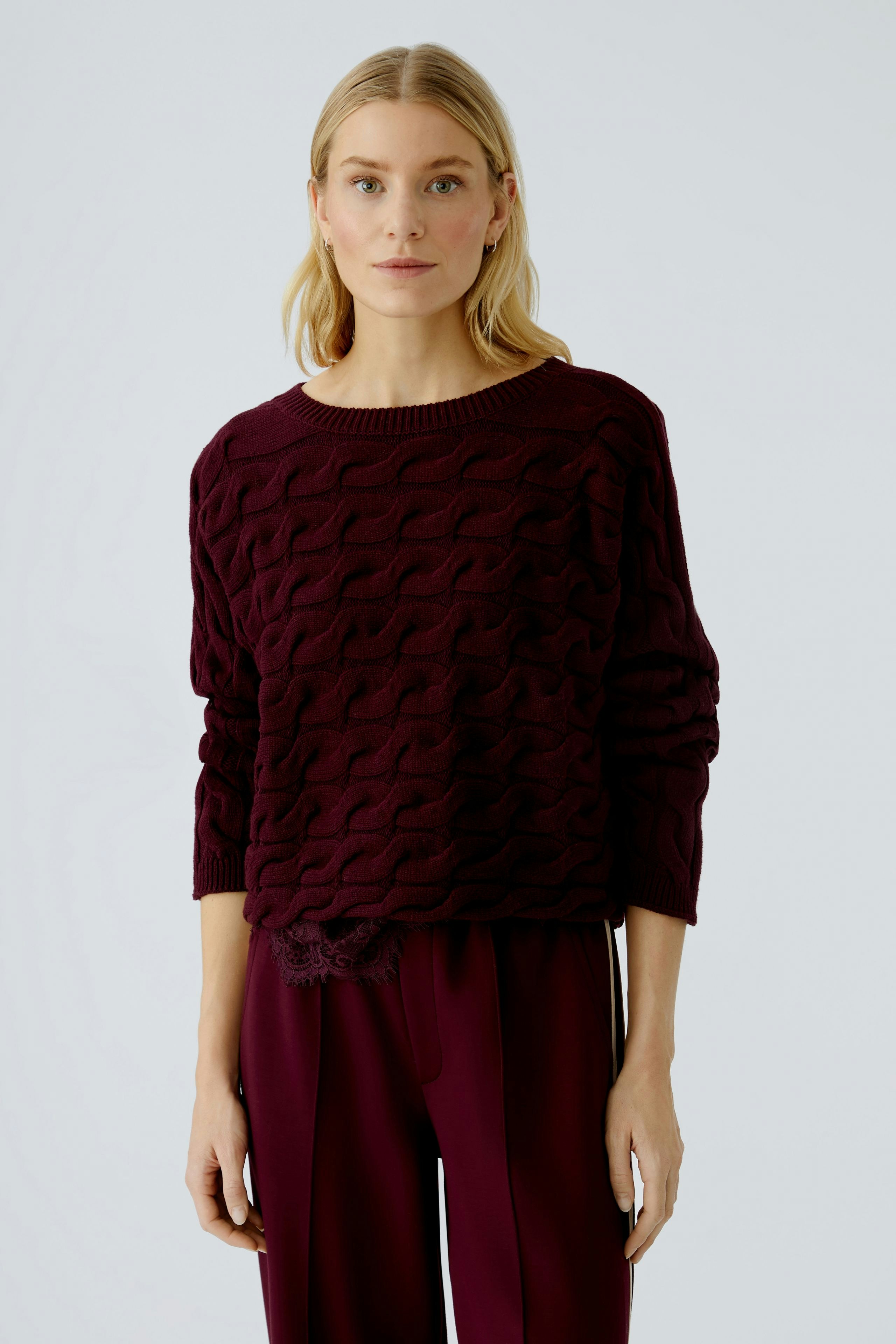 Casual women's pullover: A woman in a burgundy textured pullover paired with relaxed trousers.
