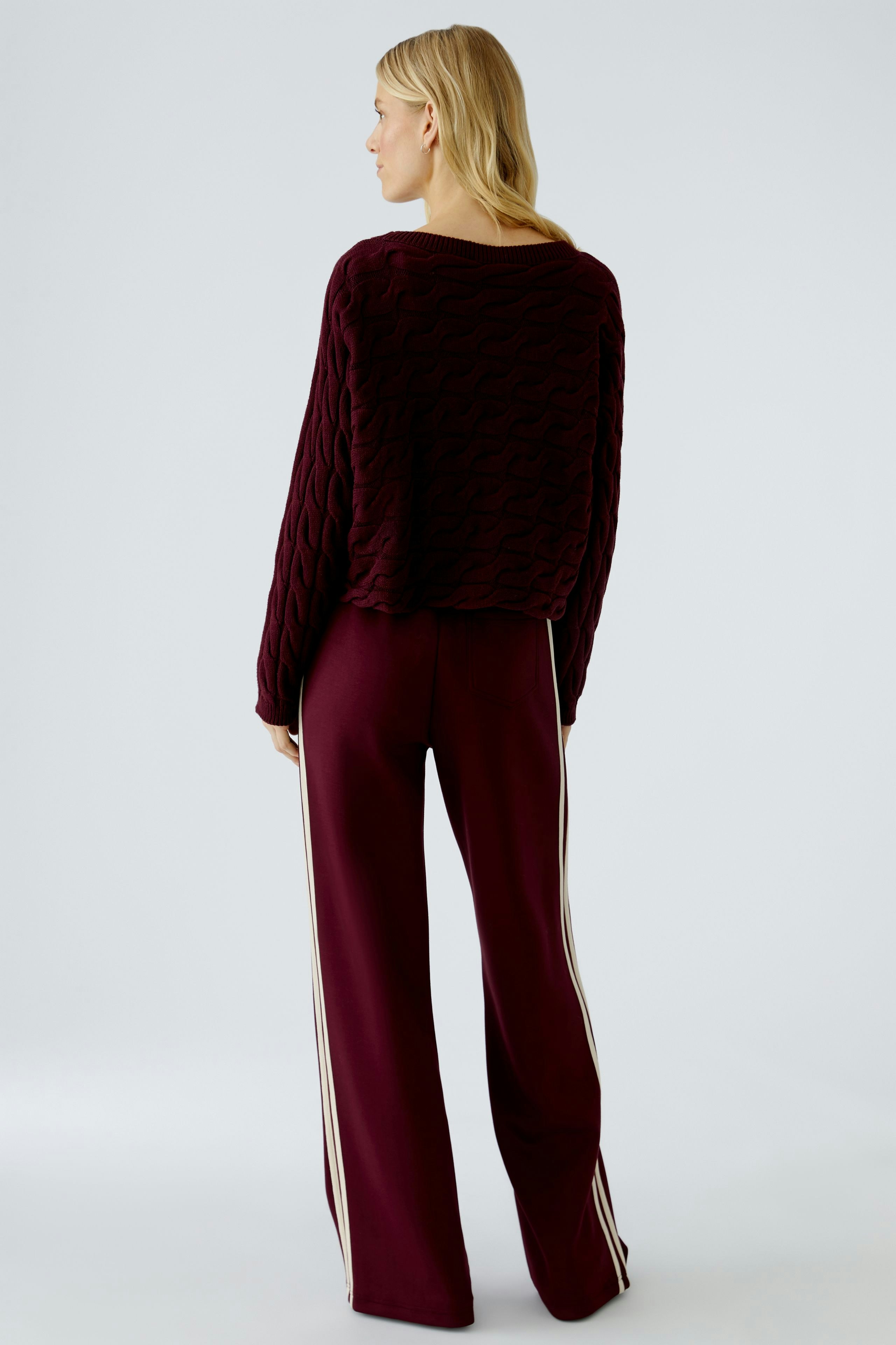 Casual women's pullover: A woman in a burgundy textured pullover and matching pants, viewed from the back.