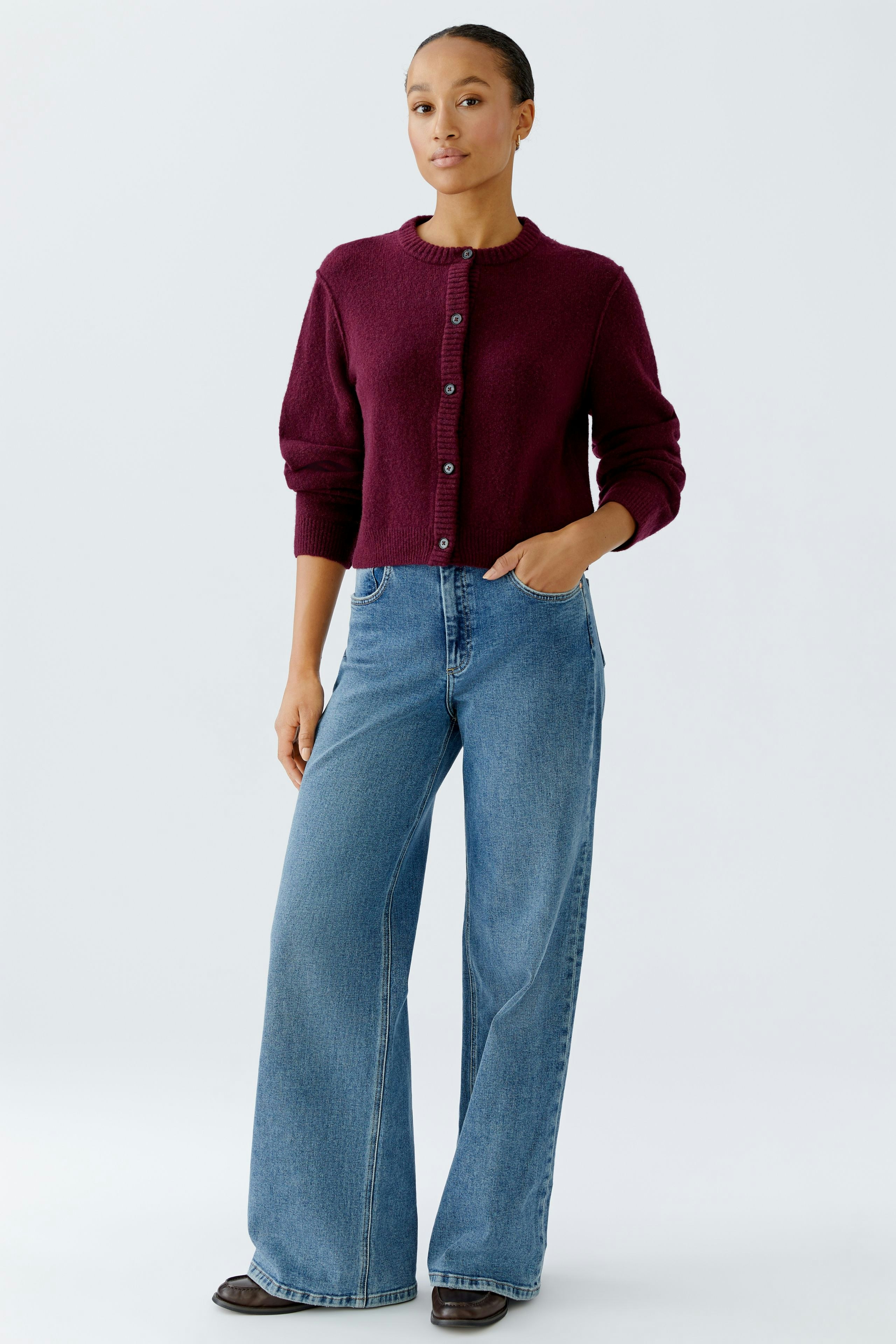 5-Pocket Hose: Junge Frau in lässiger Jeans mit weitem Bein und Hemd, steht selbstbewusst.