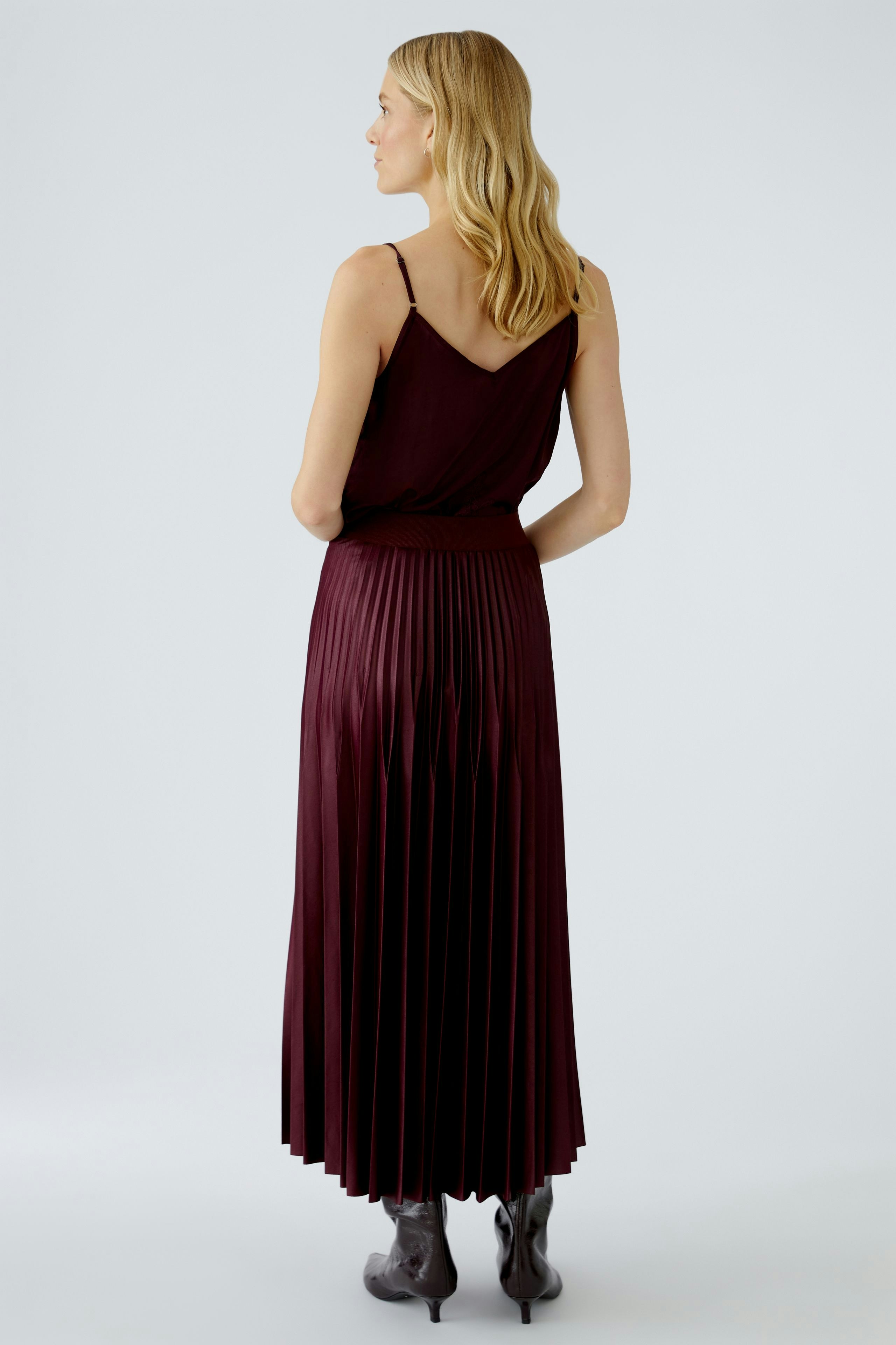 Stylish women's pleated skirt in burgundy, paired with a simple top, showcasing a flowing silhouette.