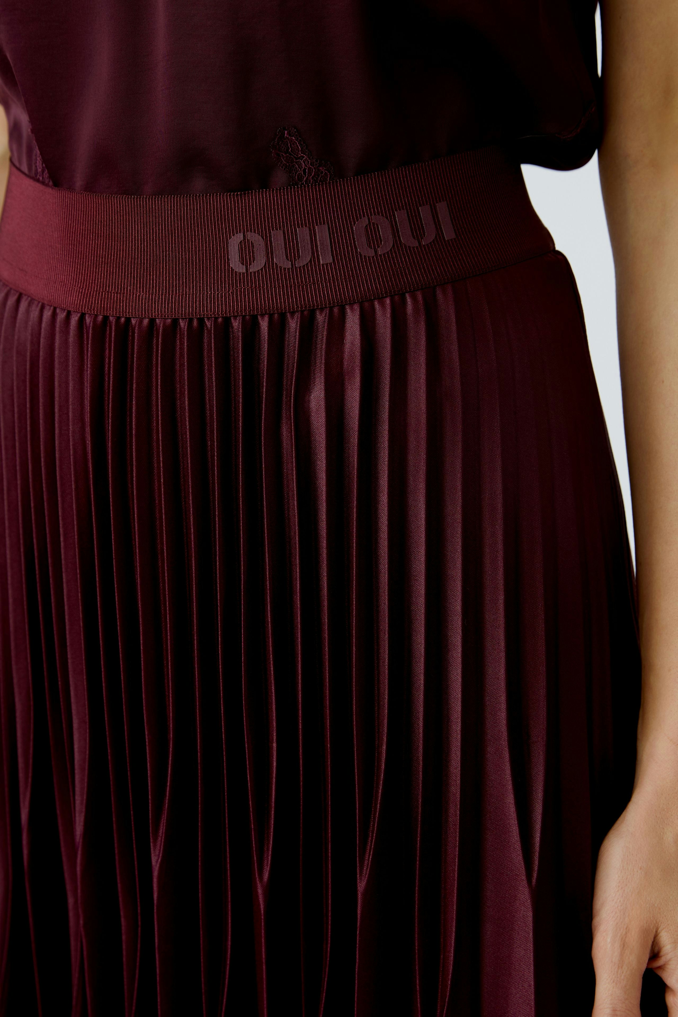 Pleated skirt: A woman wearing a burgundy pleated skirt with a comfortable waistband.