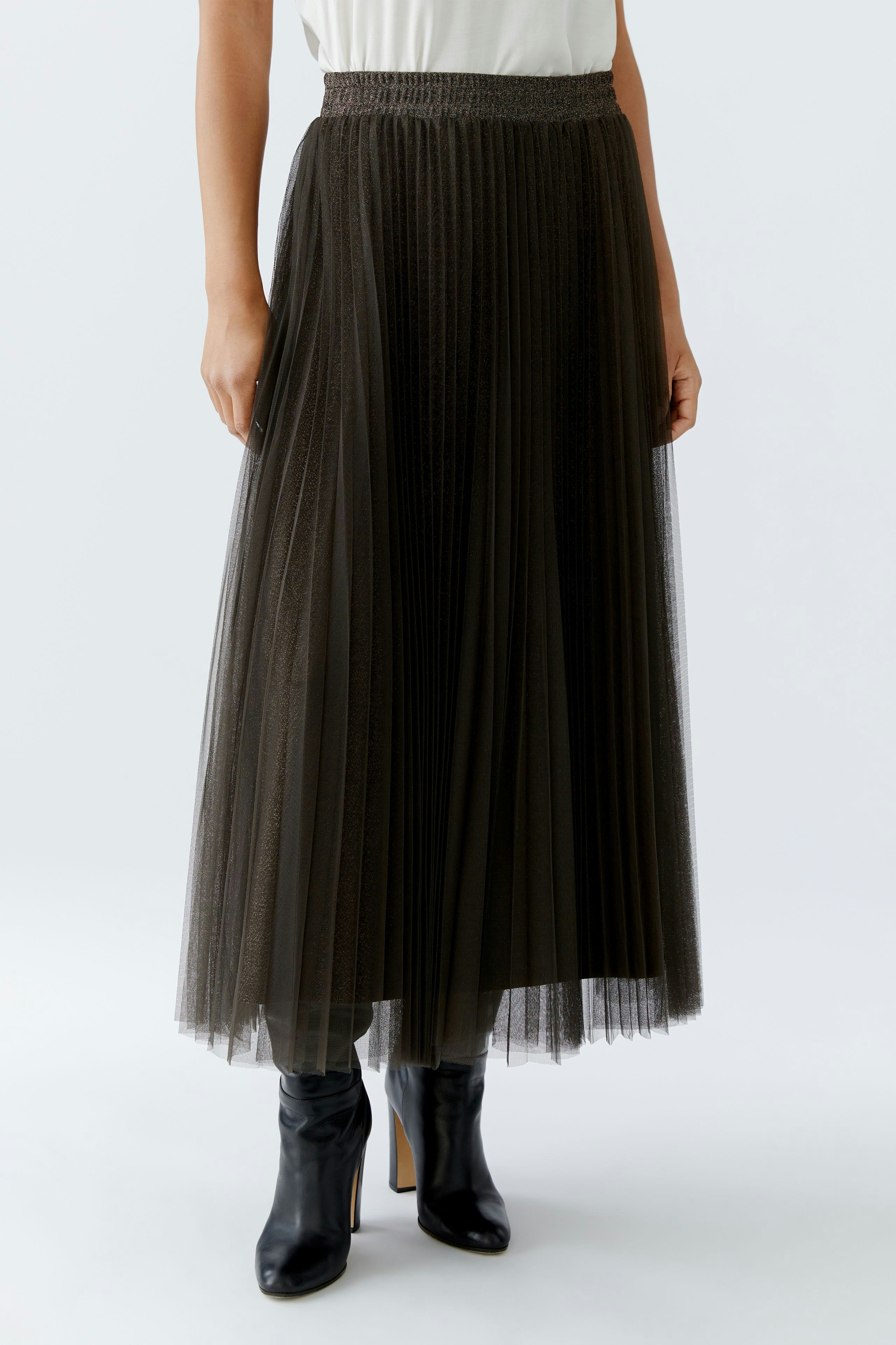 Chic women's pleated skirt: A woman in a long, dark pleated skirt paired with stylish boots.