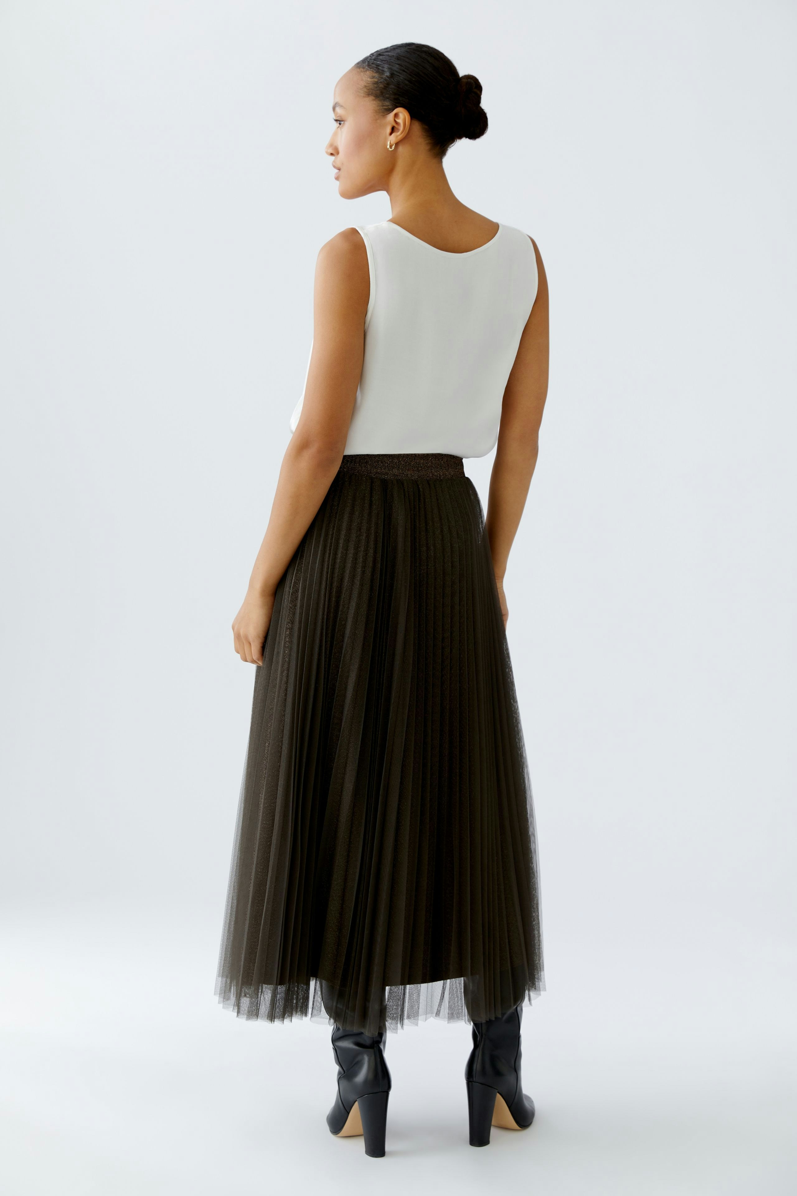 Chic pleated skirt: Woman in a long, dark pleated skirt paired with a simple top, showcasing a modern look.