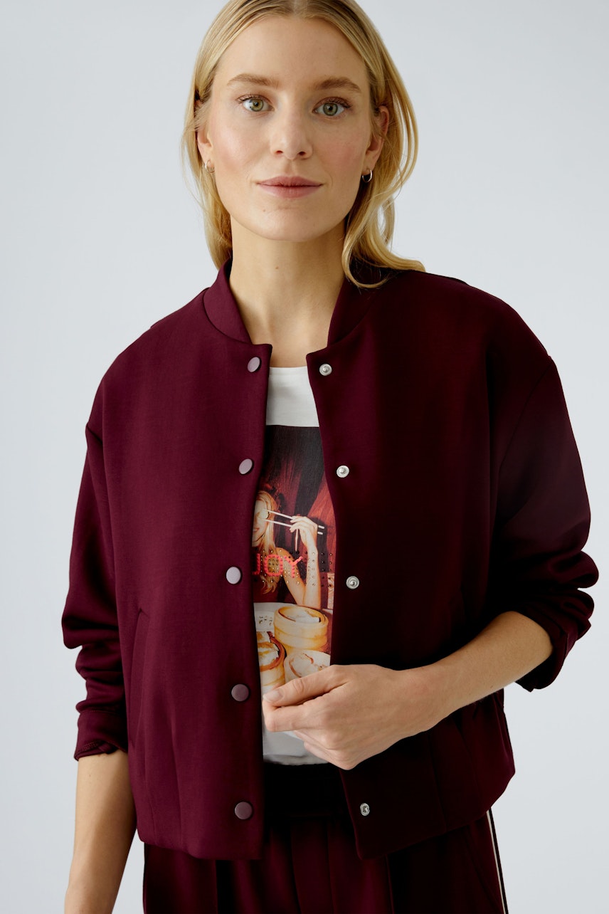 Damen-Blouson: Frau in bordeauxfarbener Bomberjacke mit lässigem Shirt und natürlichem Look.