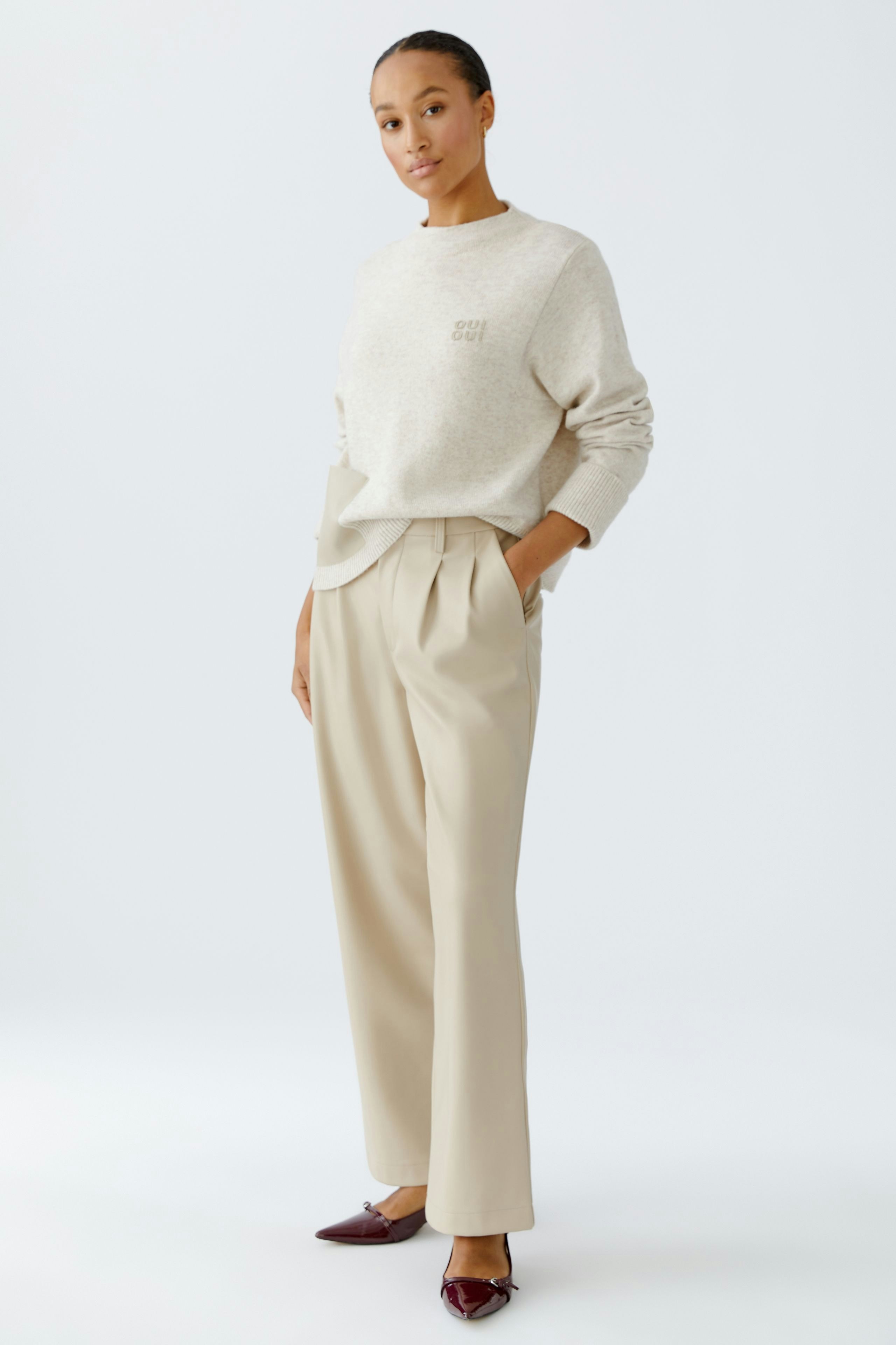Casual women's pleated trousers: A woman stands confidently in beige trousers with a relaxed fit.