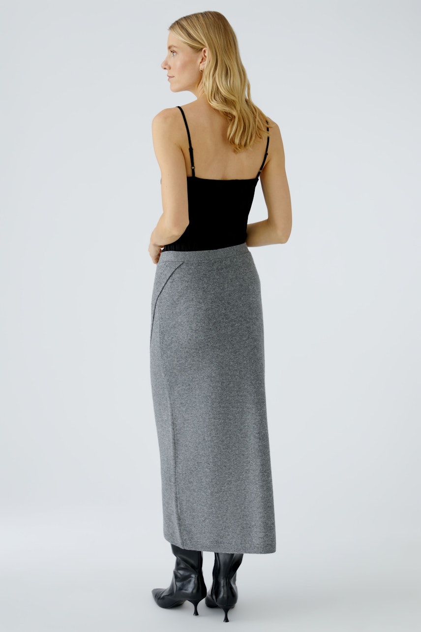 Damen-Strickrock: Frau in grauem, langem Strickrock mit seitlichem Schlitz und schwarzem Top.