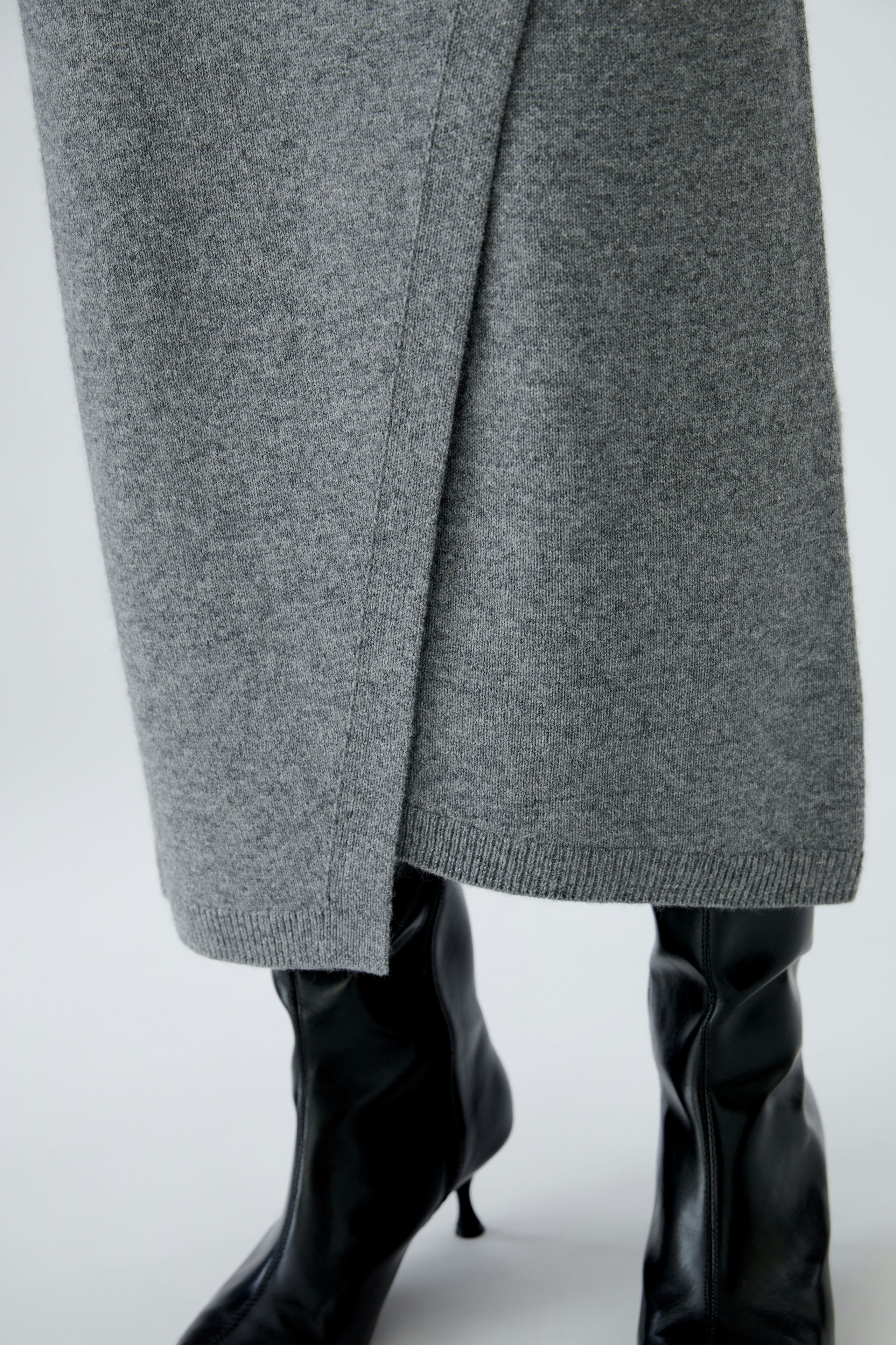 Casual women's knitted skirt in grey, paired with stylish black boots.
