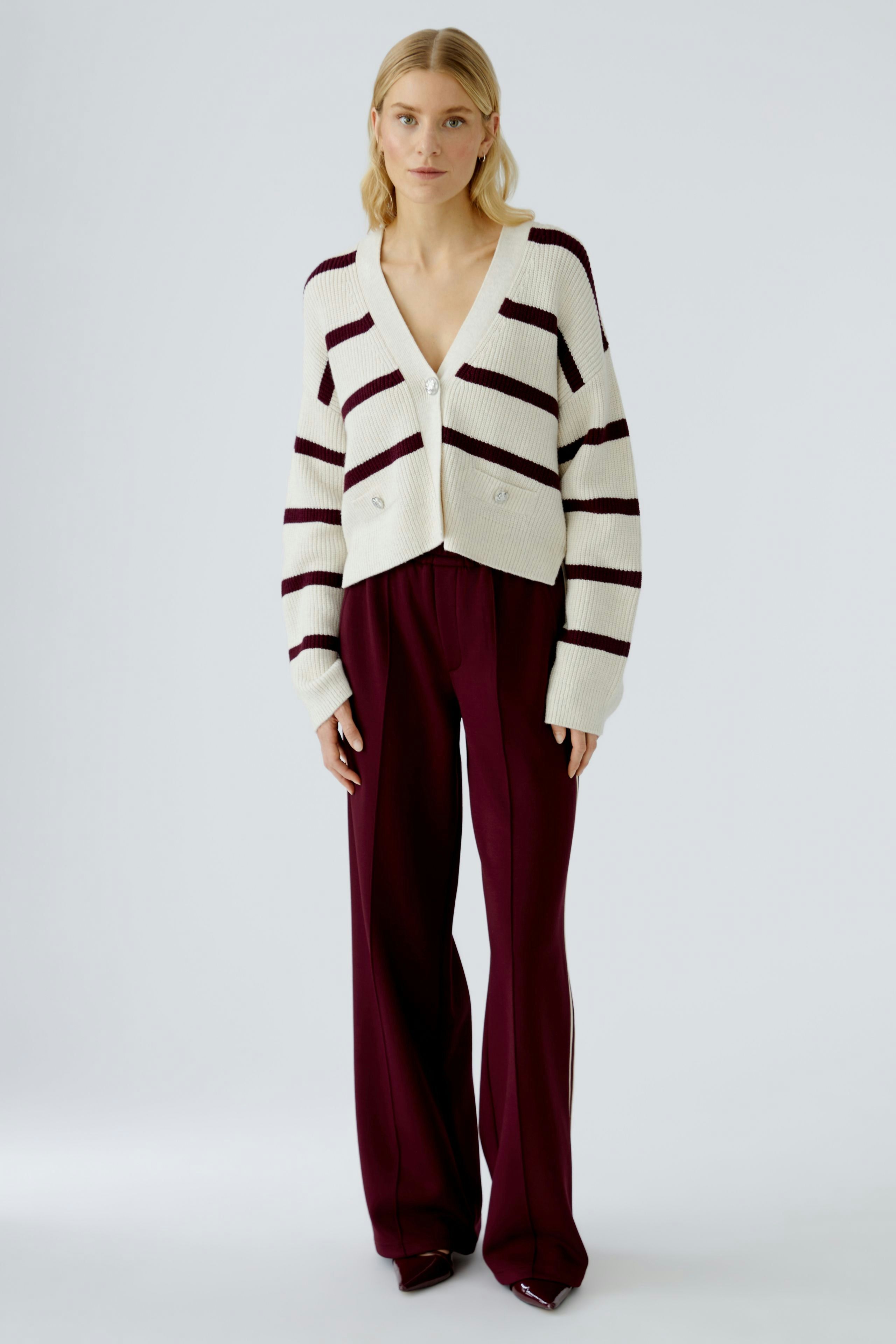 Casual women's cardigan: A woman in a striped cardigan with a deep V-neck and buttons, paired with wide trousers.