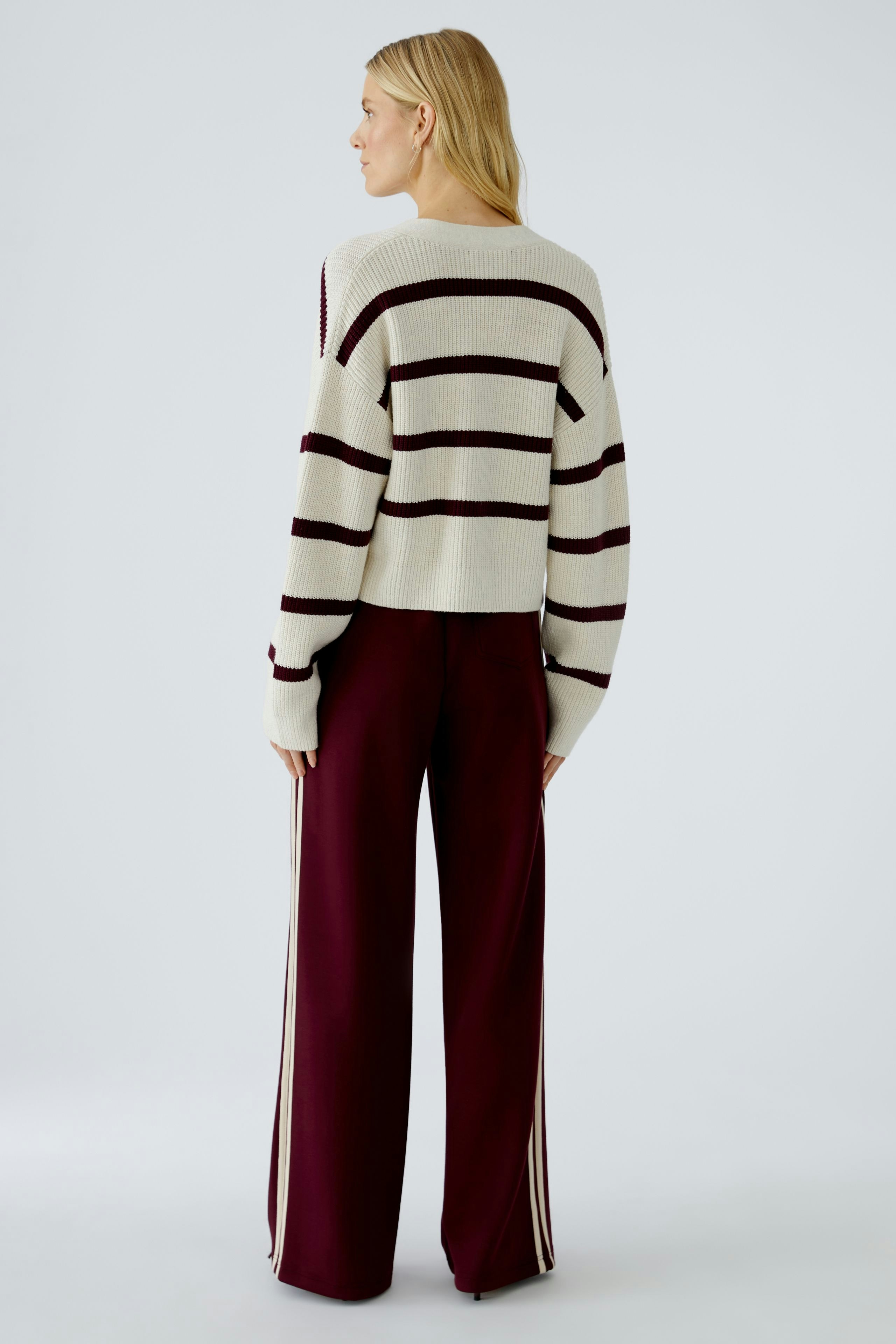 Casual women's cardigan: A woman in a striped pullover with a relaxed fit, paired with wide trousers.