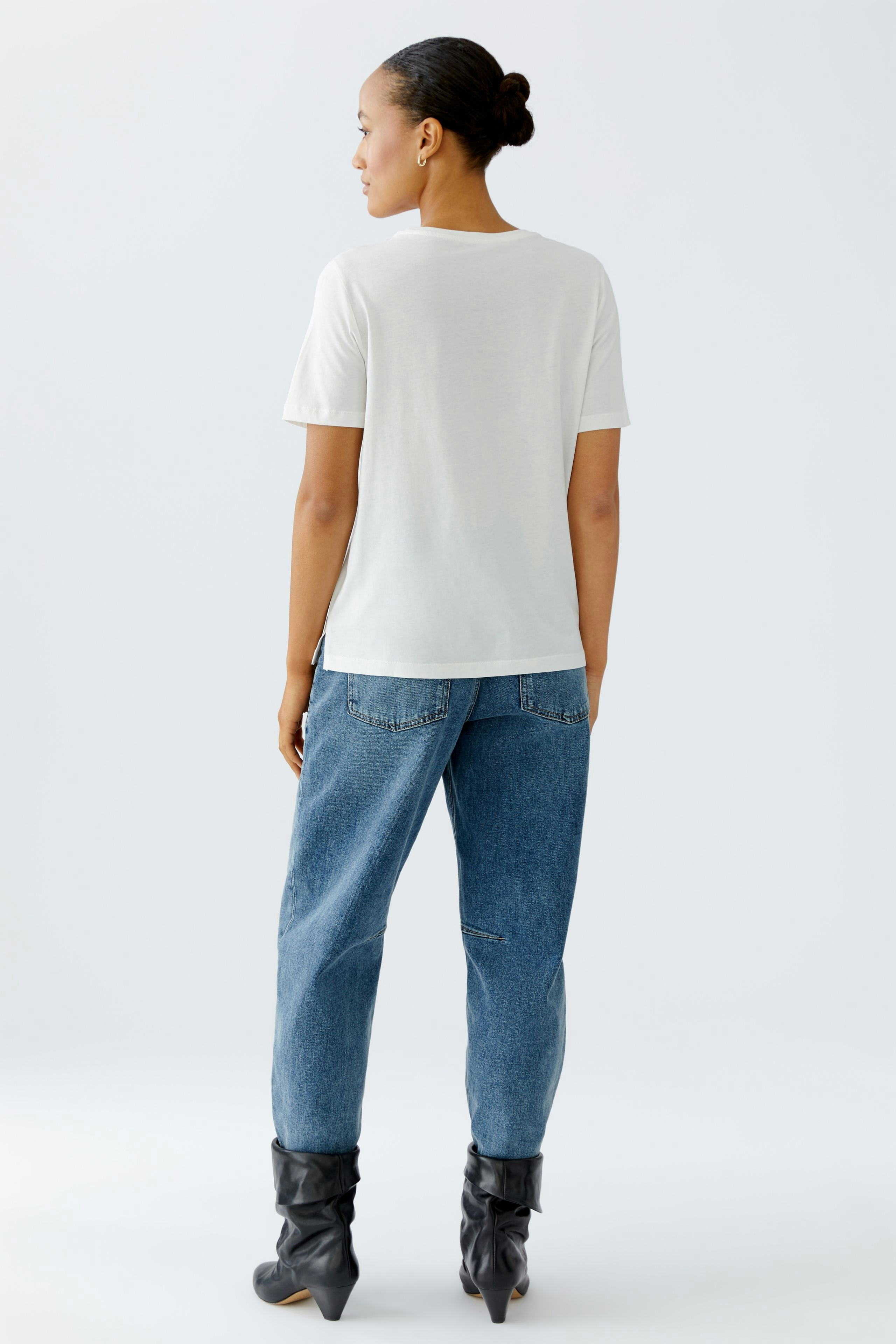 Bequemer Damen-T-Shirt: Frau in weißem T-Shirt und lässigen Jeans von hinten.
