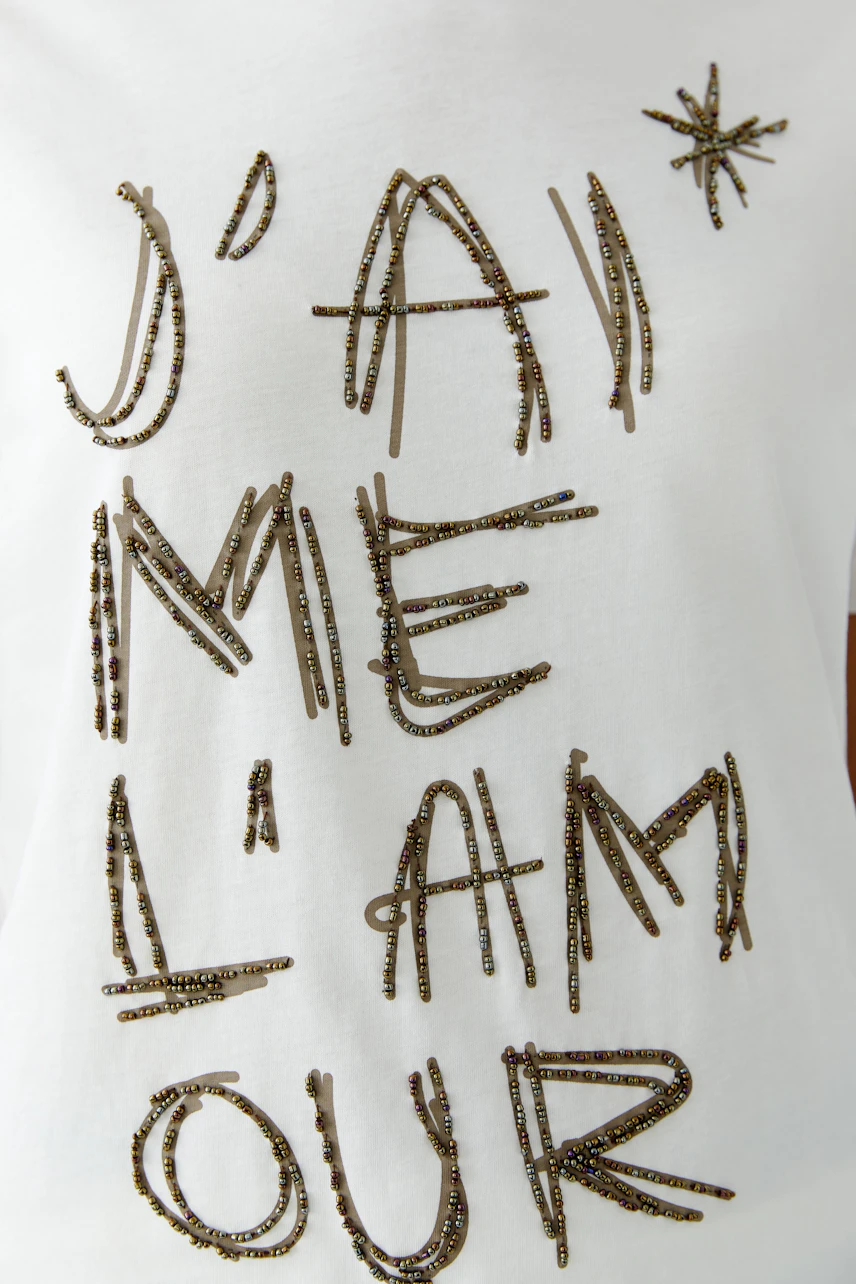 Casual women's t-shirt: A woman in a white shirt with stylish text design, showcasing a relaxed look.
