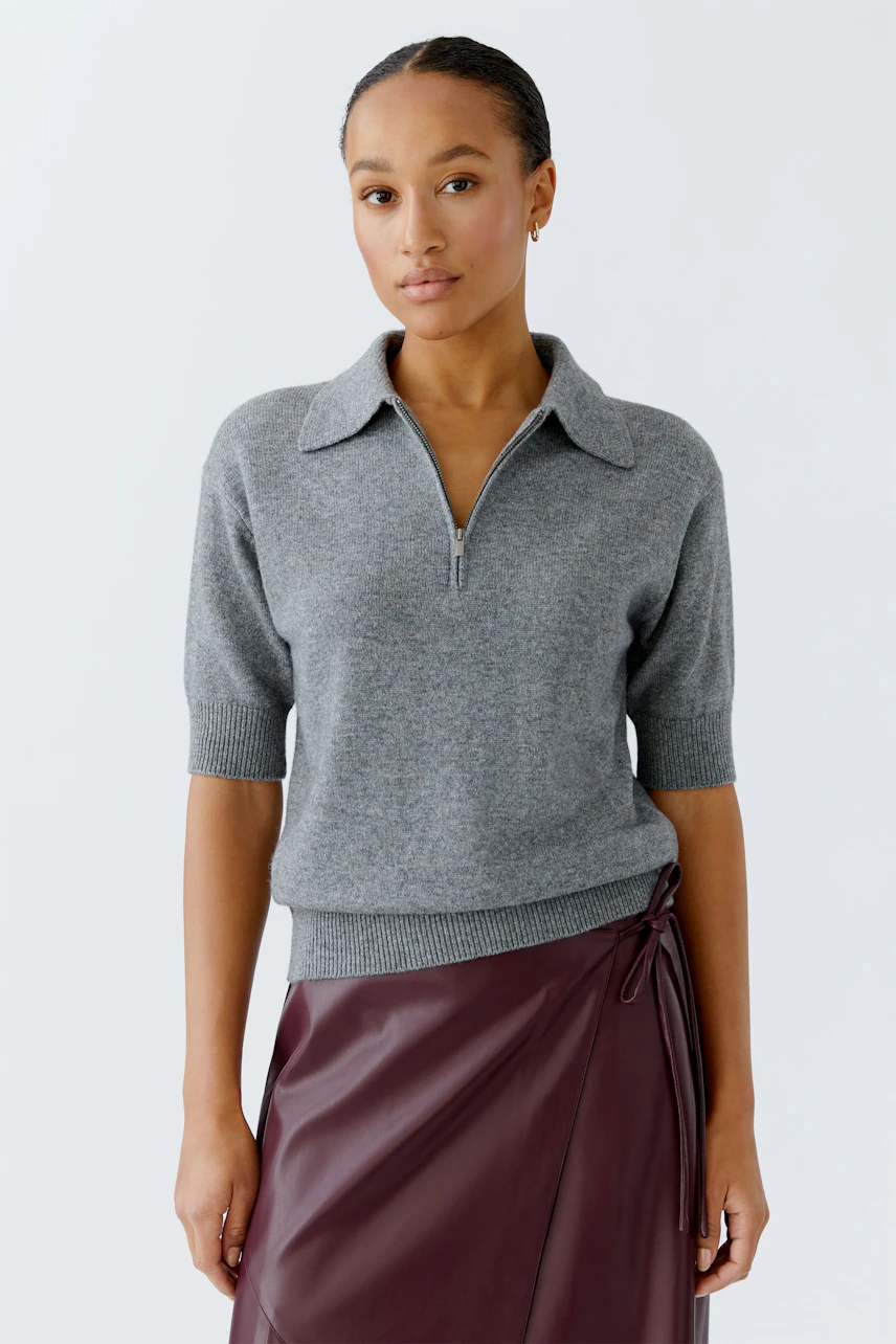Casual women's pullover: Young woman in a gray short-sleeve pullover with a zip collar.