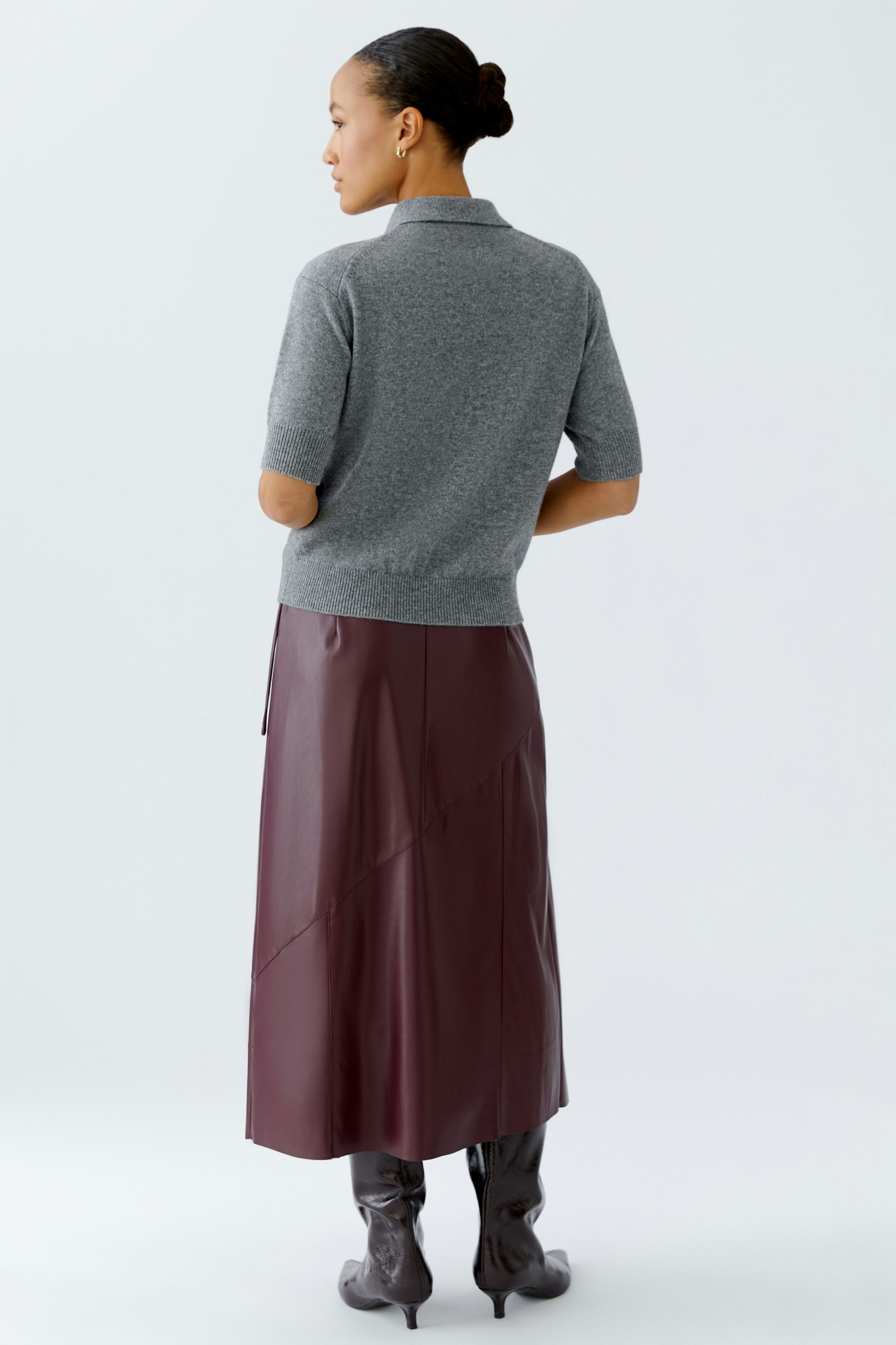 Damen-Pullover: Frau in grauem, kurzärmligem Pullover mit lässigem Schnitt und modischer Lederrock.