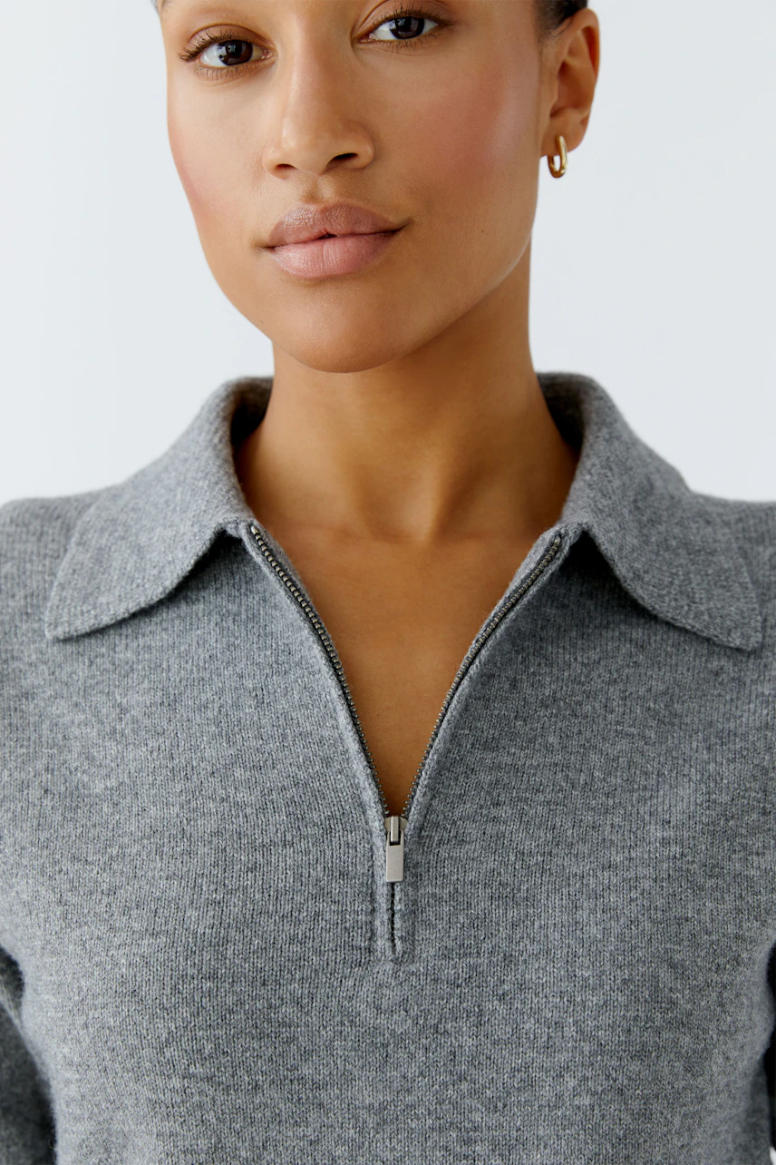 Casual women's pullover: Close-up of a woman in a gray pullover with a zip collar, showcasing a relaxed style.