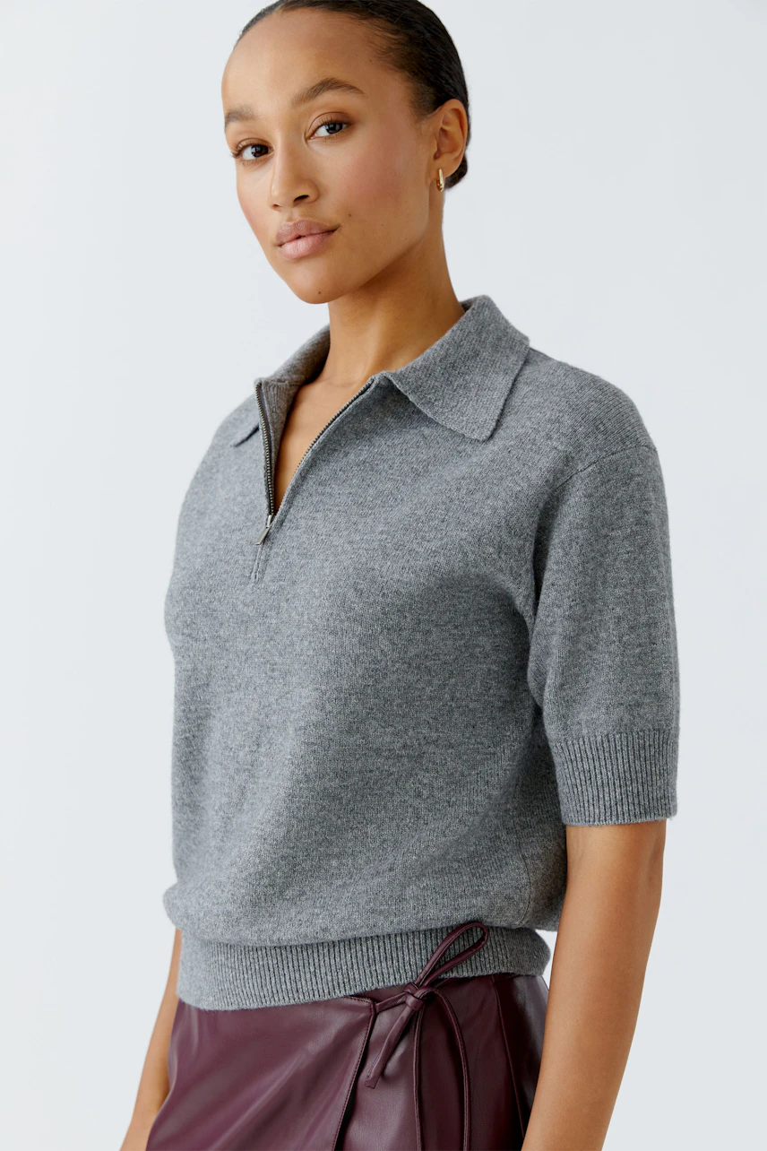 Casual women's pullover: Young woman in a gray short-sleeve pullover with a collar, looking confidently.