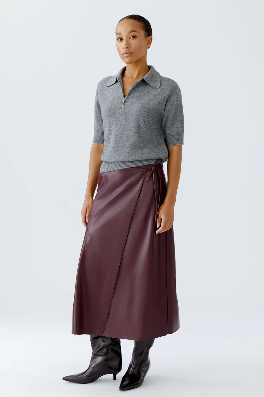 Casual women's pullover: Woman in a gray short-sleeve pullover with a collar, paired with a stylish skirt.