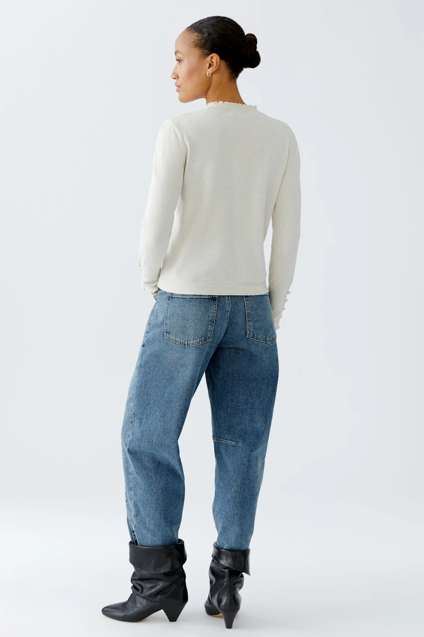 Damen-Pullover: Frau trägt einen hellen, schlichten Pullover mit Knöpfen und lässigen Jeans.