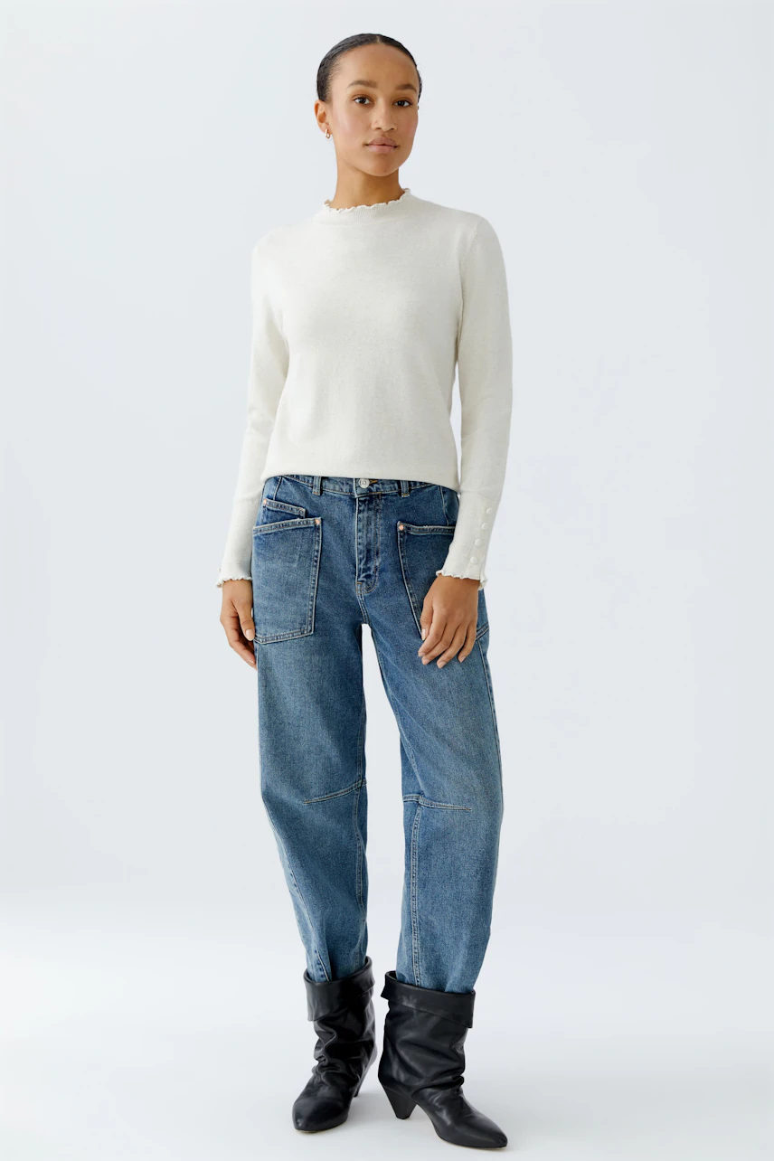 Damen-Pullover: Frau in cremefarbenem Pullover mit Rundhalsausschnitt und lässigen Jeans.